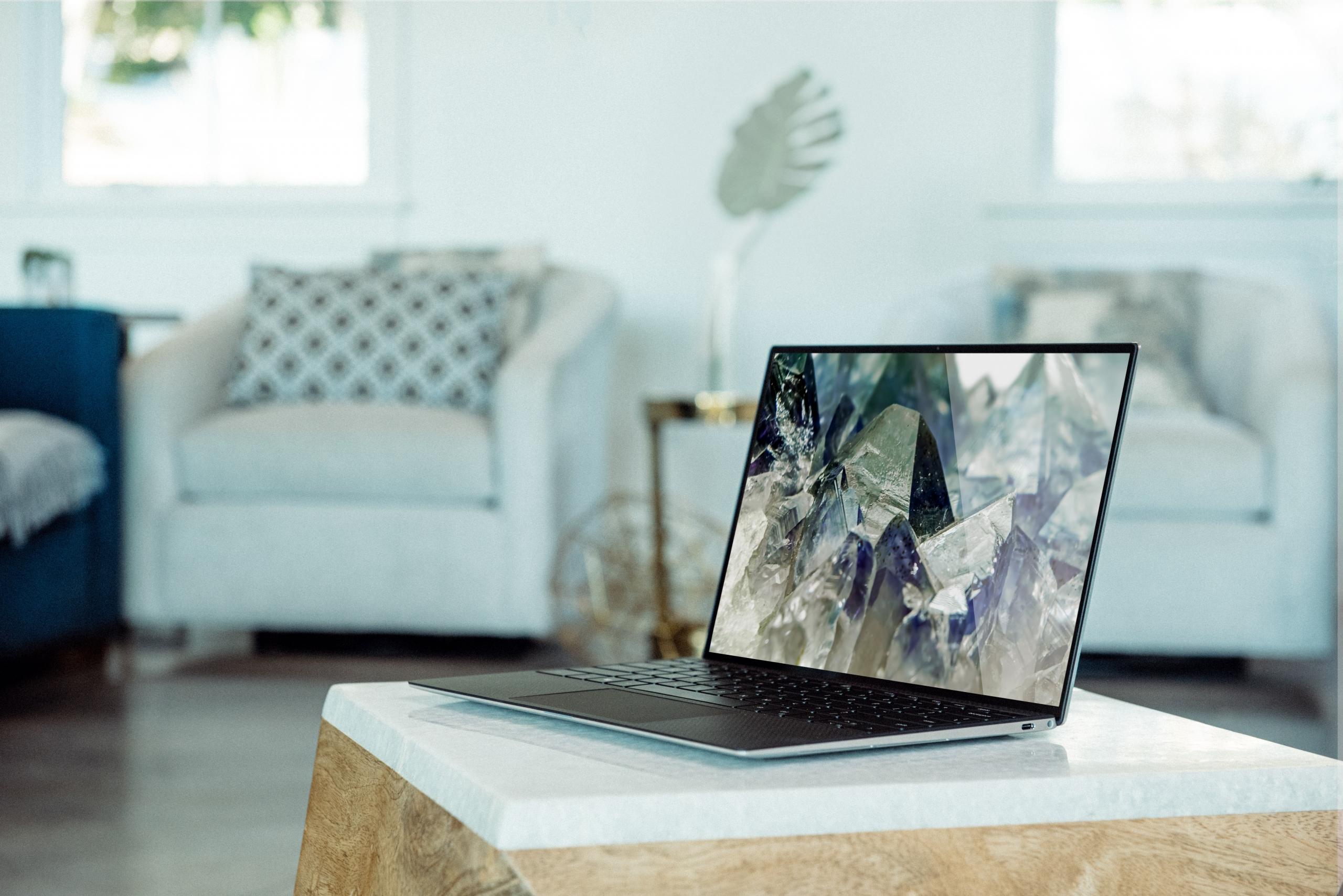 en laptop står på et lavt stuebord, det står en stol i bakgrunnen
