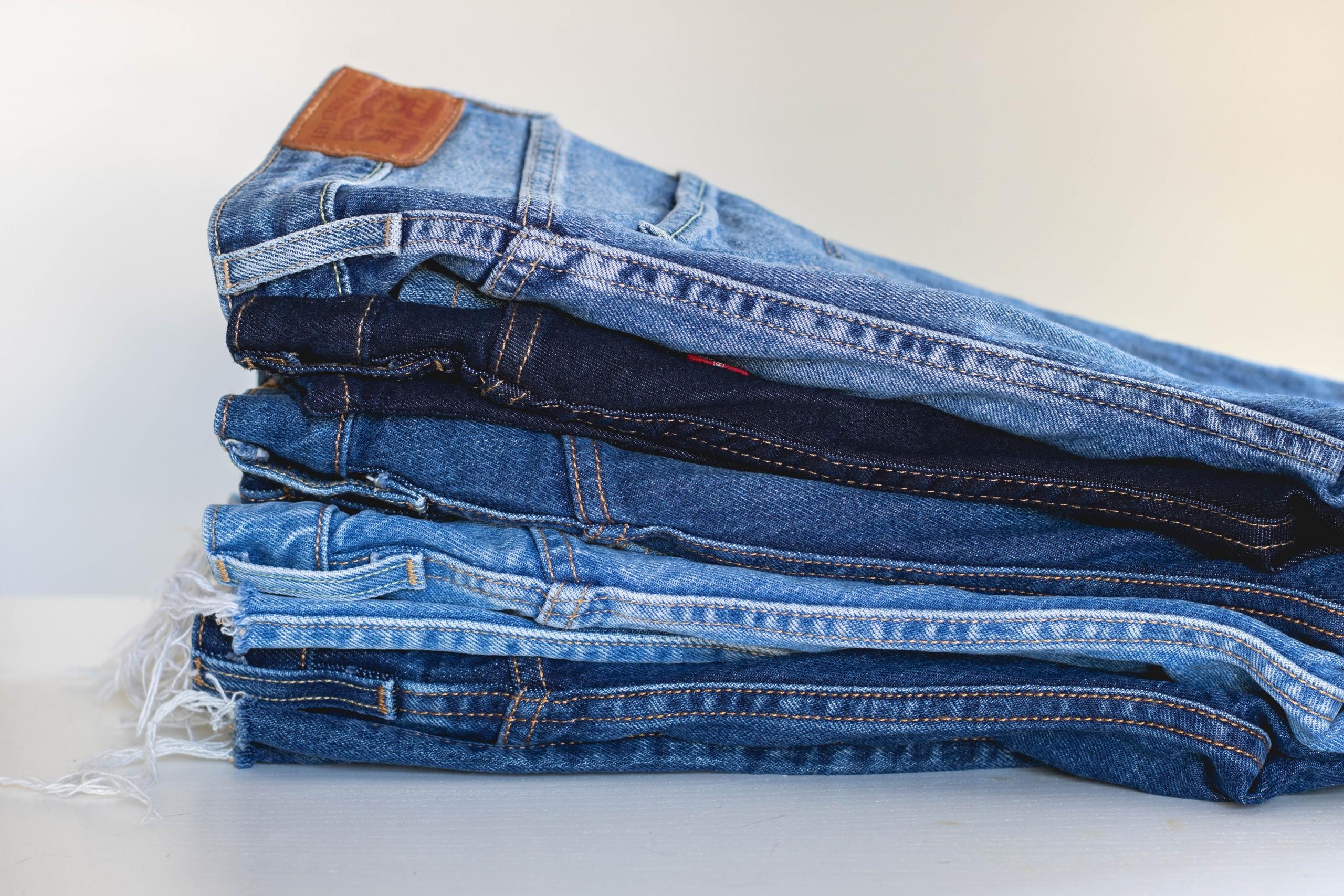 sammenbrettede jeans ligger i en stabel, i bretten er det en dobbel søm