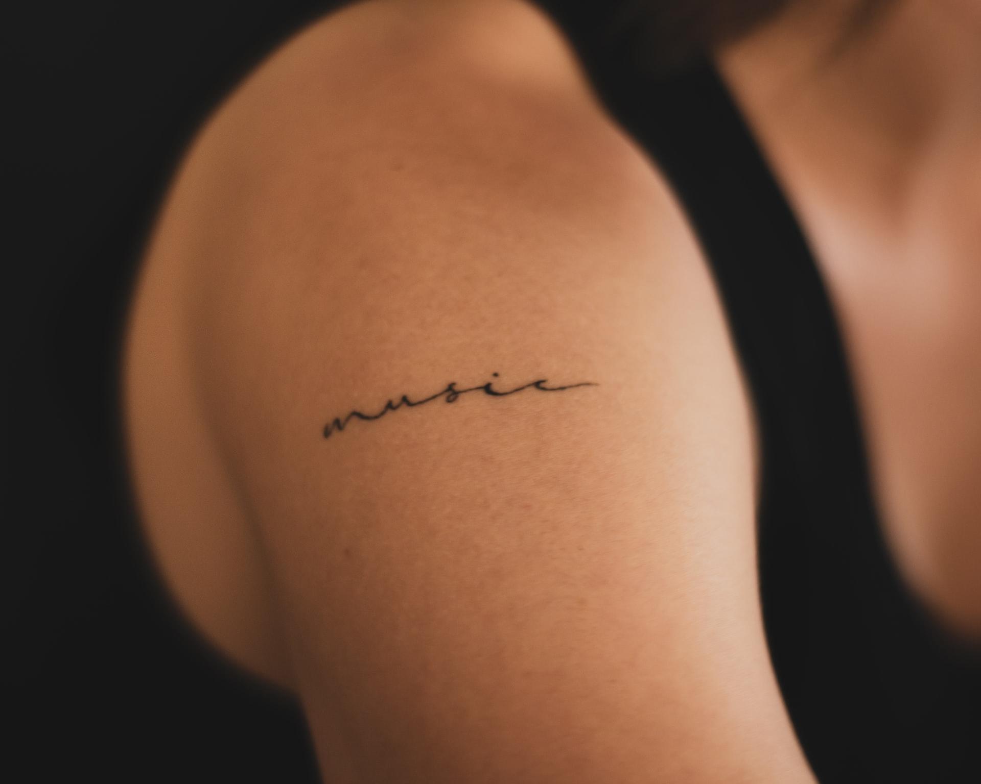 En bar skulder med en tynn tatovering av tekst