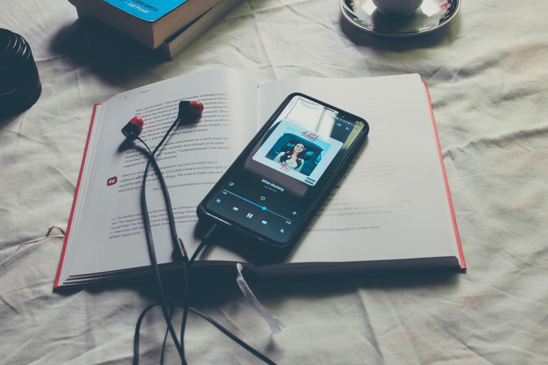 En bok med en telefon som spiller musikk liggende på et laken