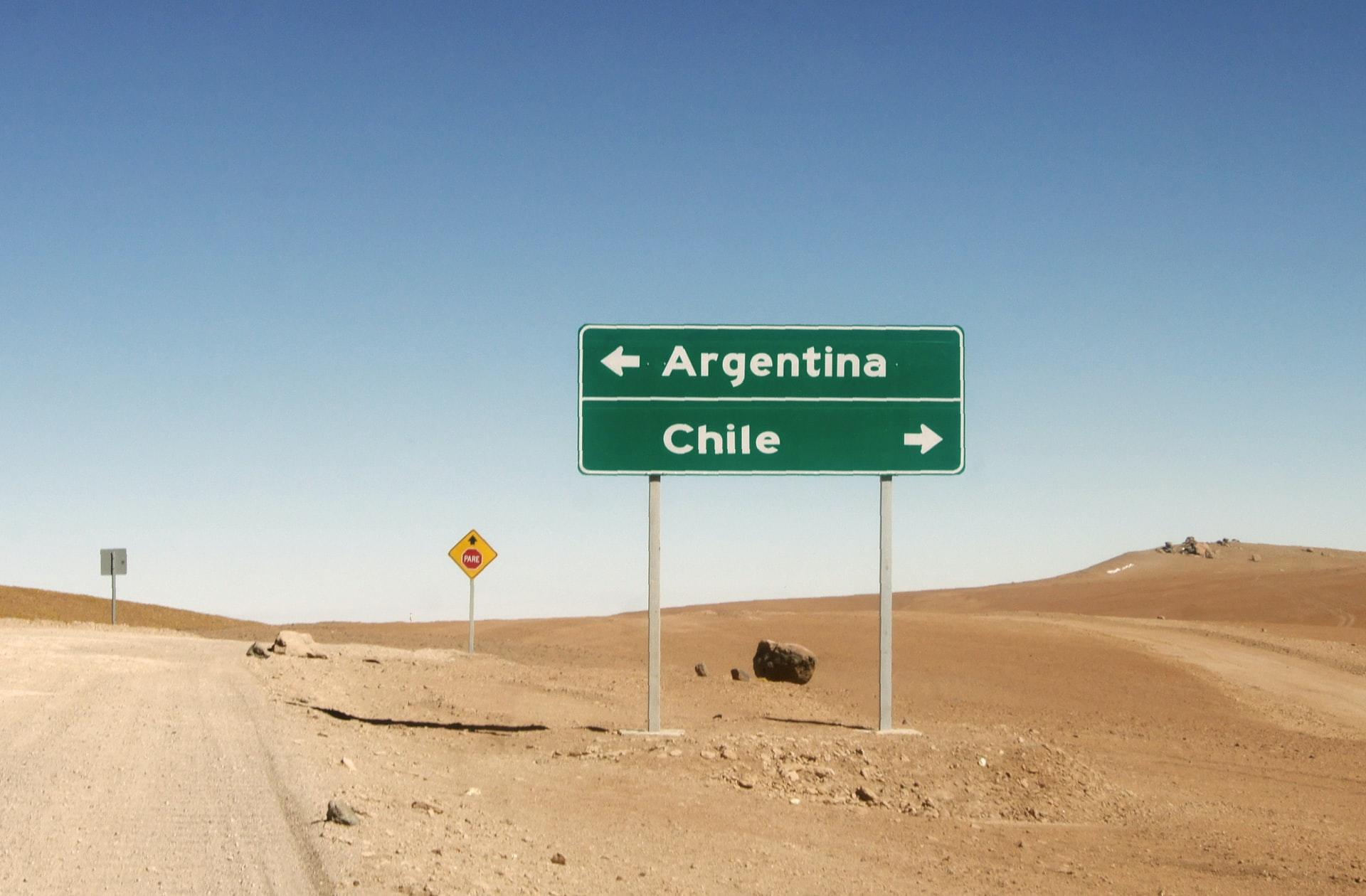 En ørken med et grønt veiskilt som viser veien til Argentina (venstre) og Chile (høyre)