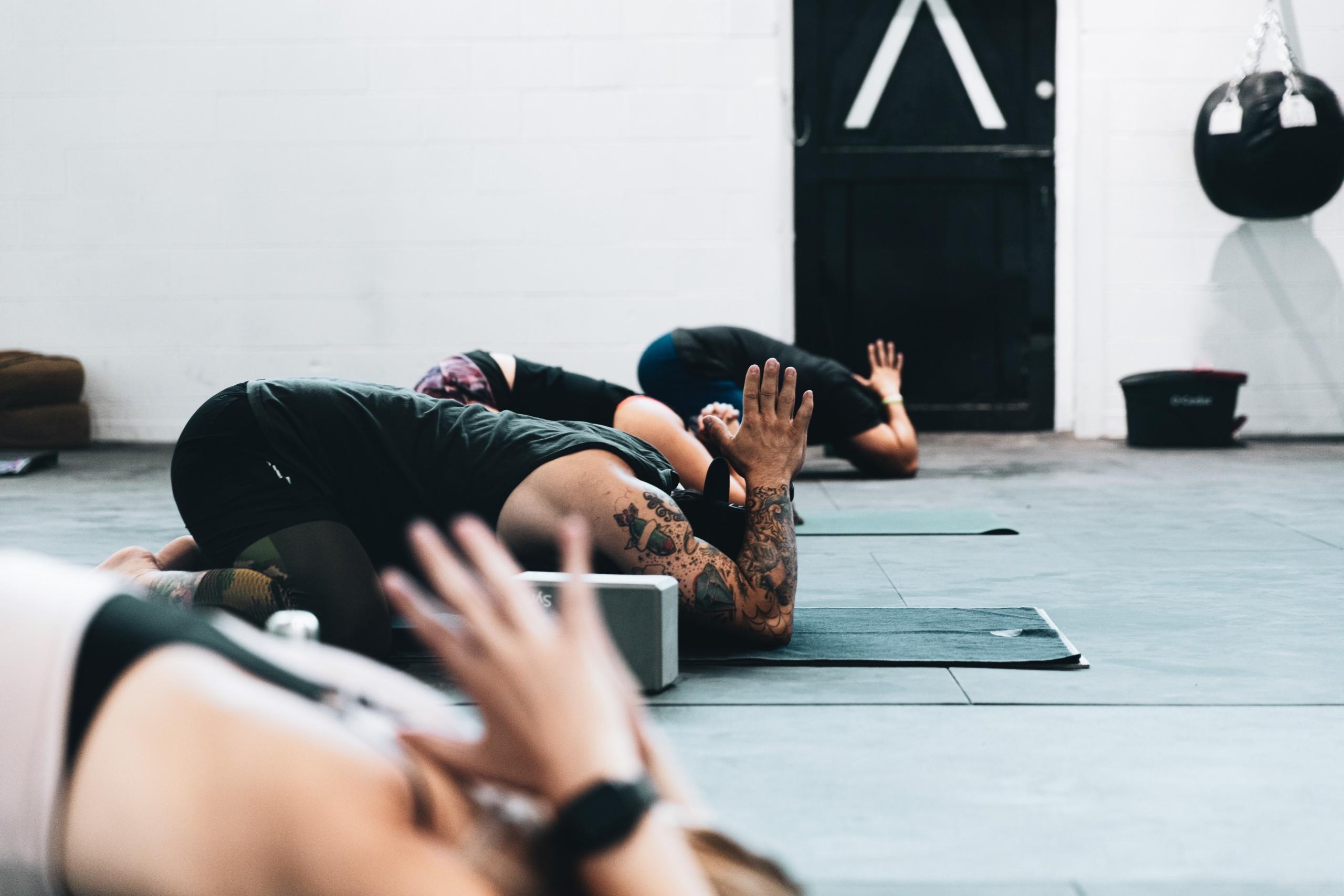 tre personer gjør yoga på et treningssenter