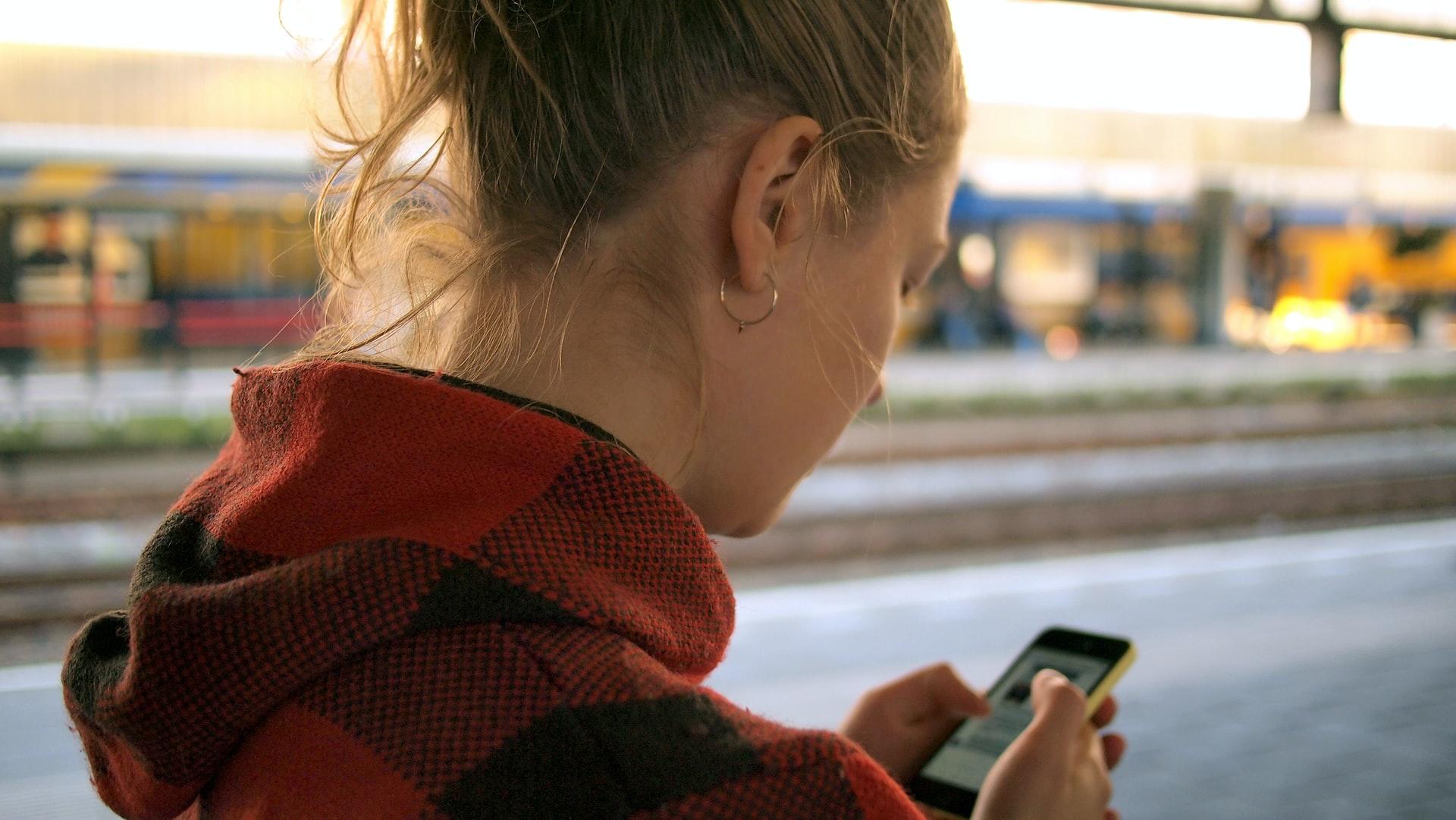 Nærbilde av en kvinne som står med ryggen til som er på mobilen