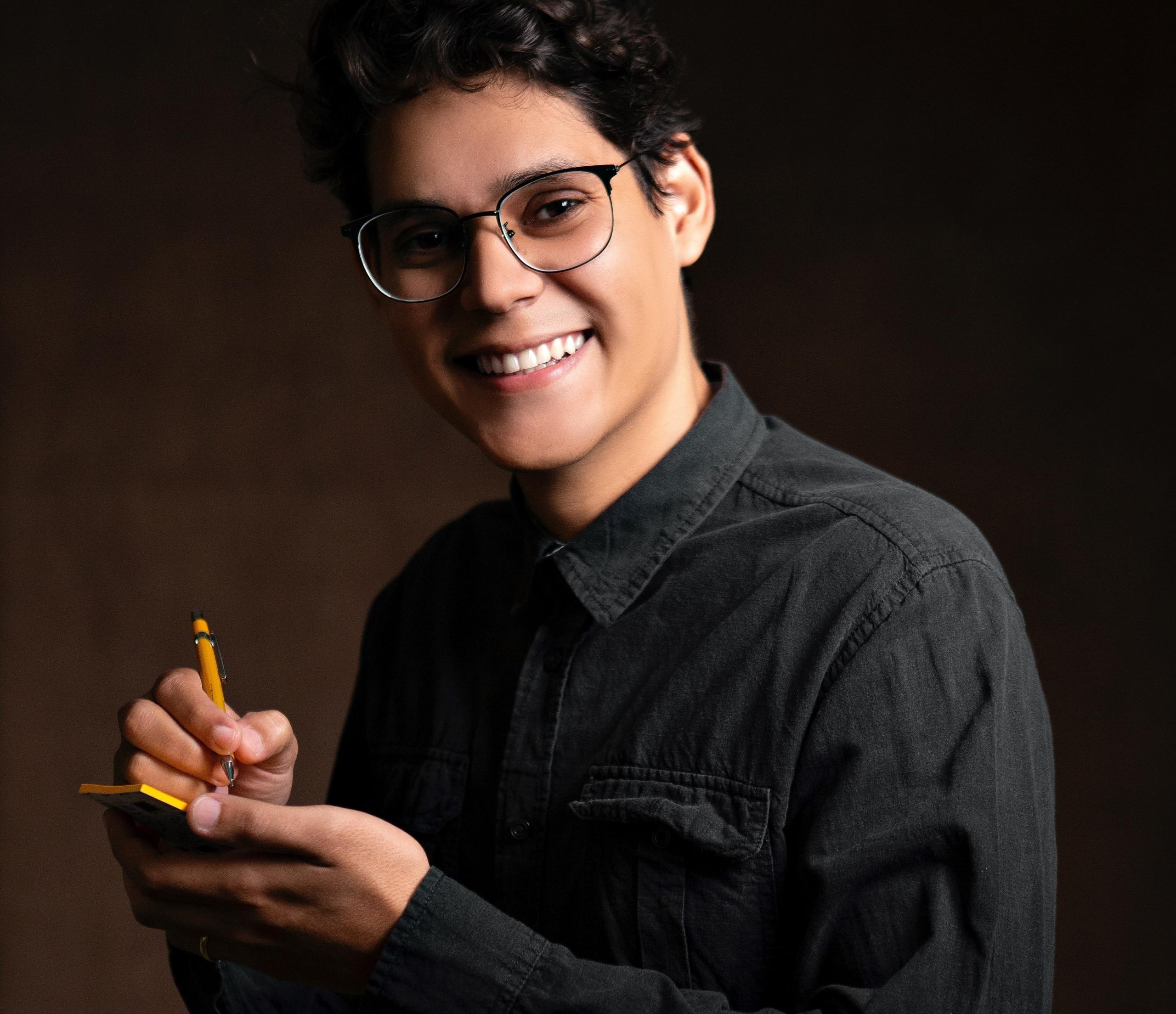 en tenåring tar timer i arabisk, han smiler og holder opp en notatblokk som han skriver i