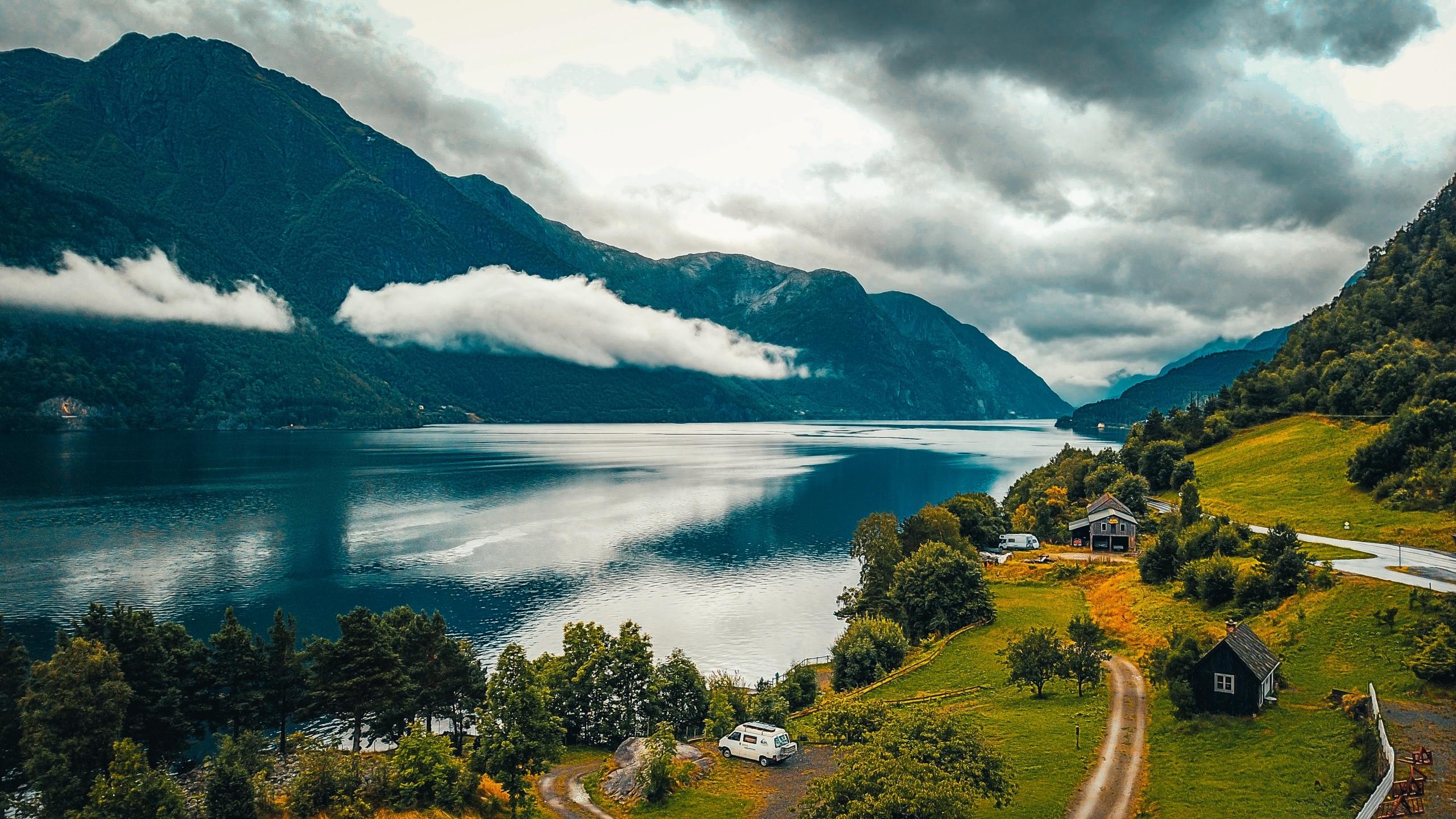 et hus ligger avsidesliggende til ved en fjord, fjellet står bratt opp på den andre siden