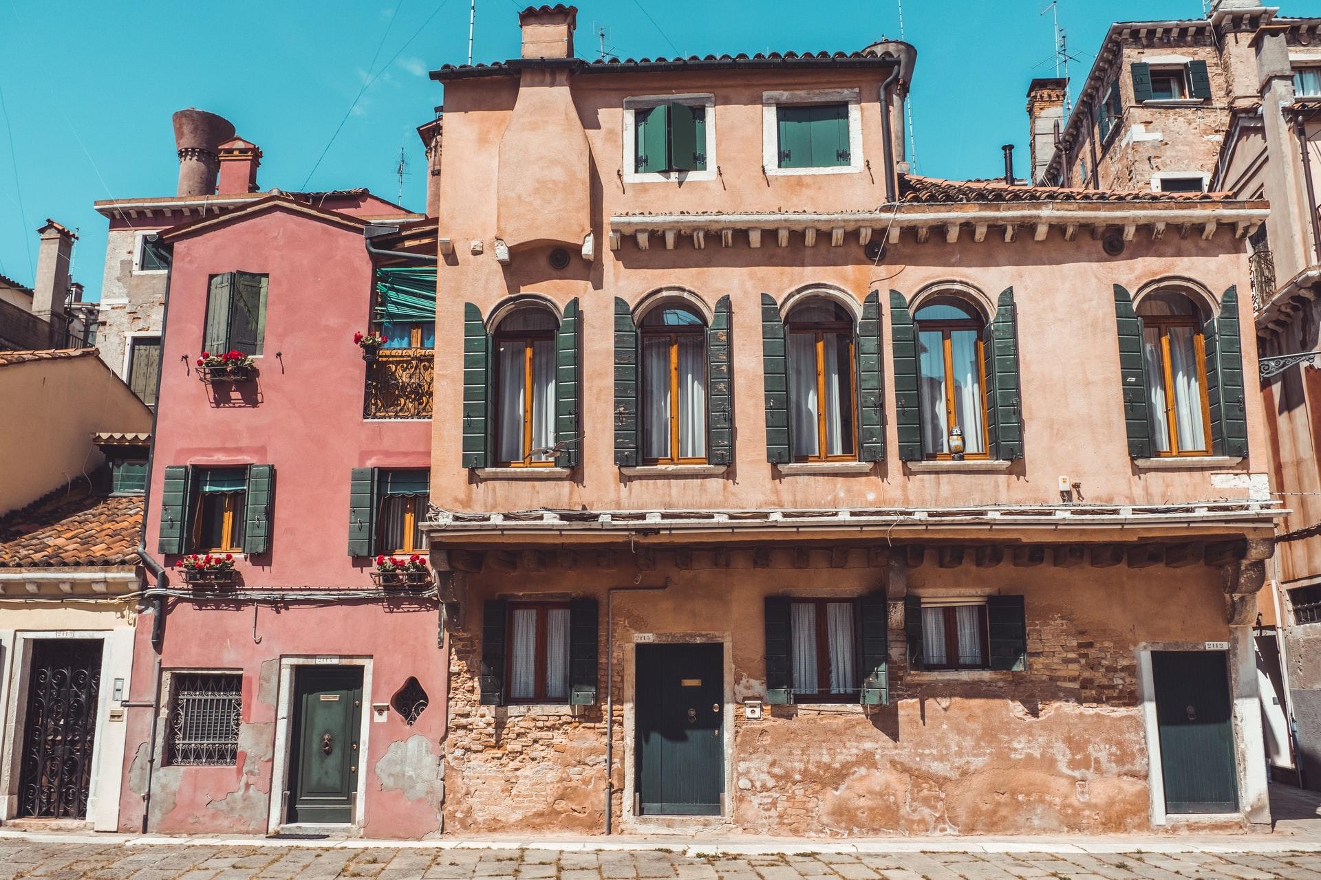 Et rosa og et oransje hus i en gate i Italia