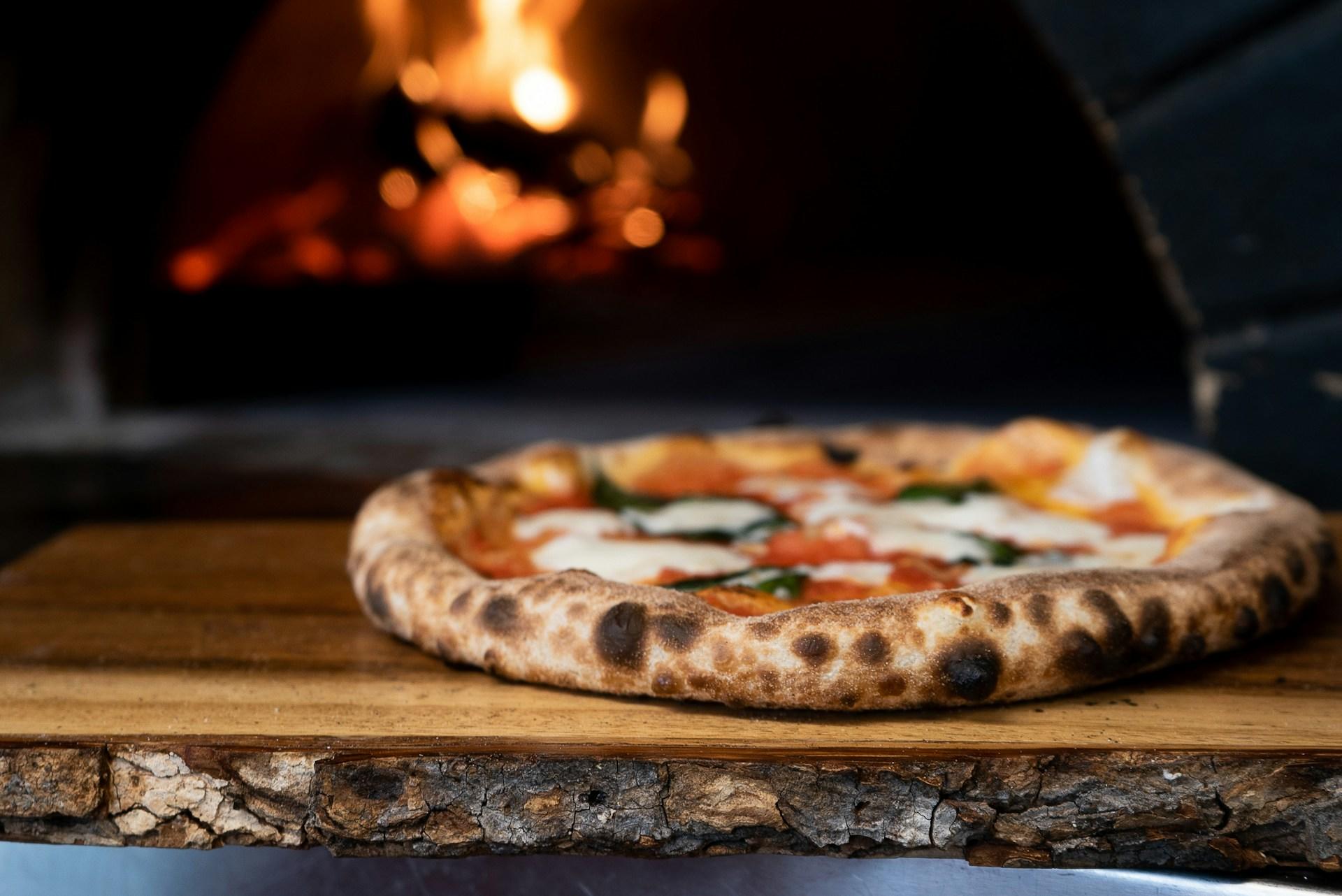Italiensk pizza margherita på vei ut av steinovnen.