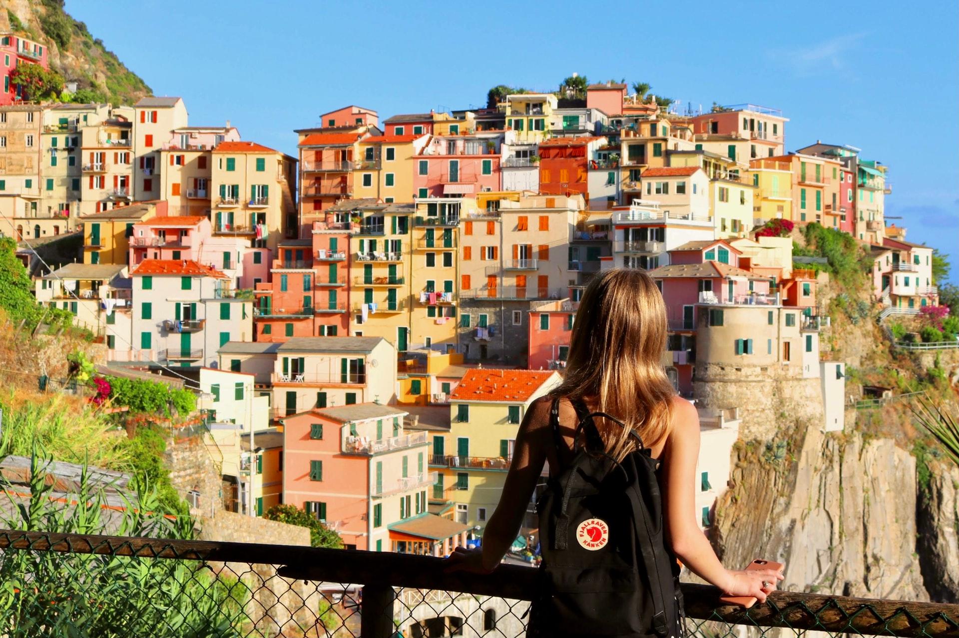 En kvinne med ryggen til som ser utover en italiensk, fargerik landsby