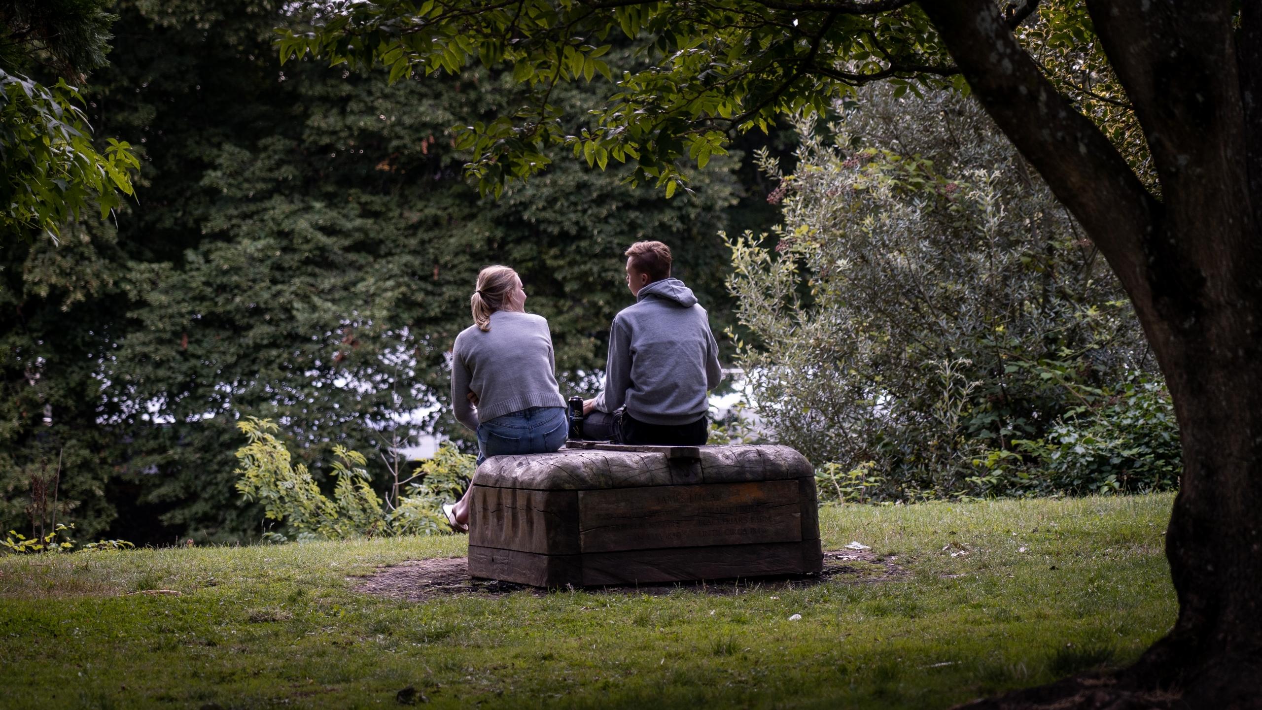 to engelskstudenter sitter på en steinbenk i en park i Cardiff