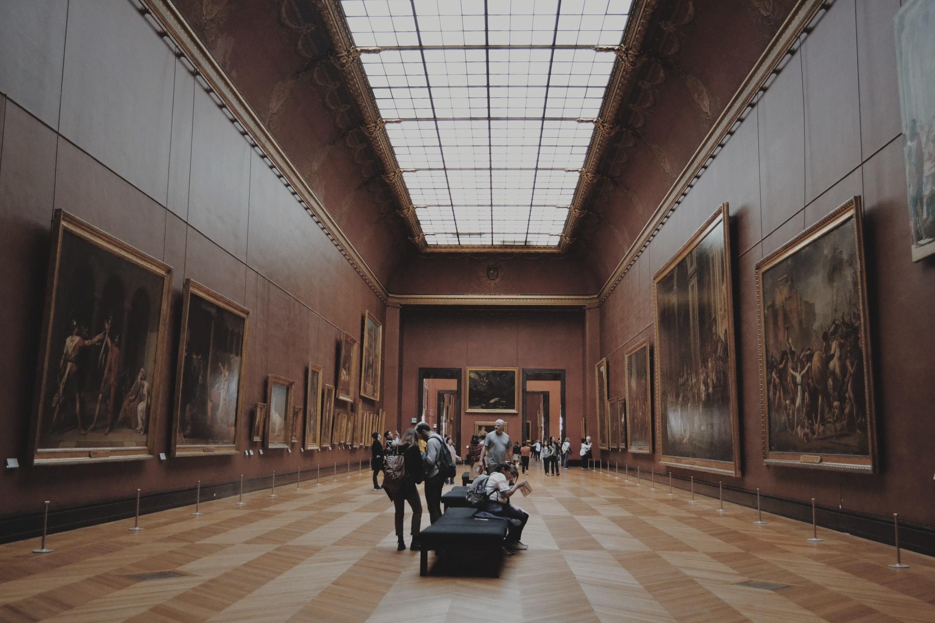 Oversiktsbilde av et stort brunt rom på et kunstmuseum med glassvinduer i taket.