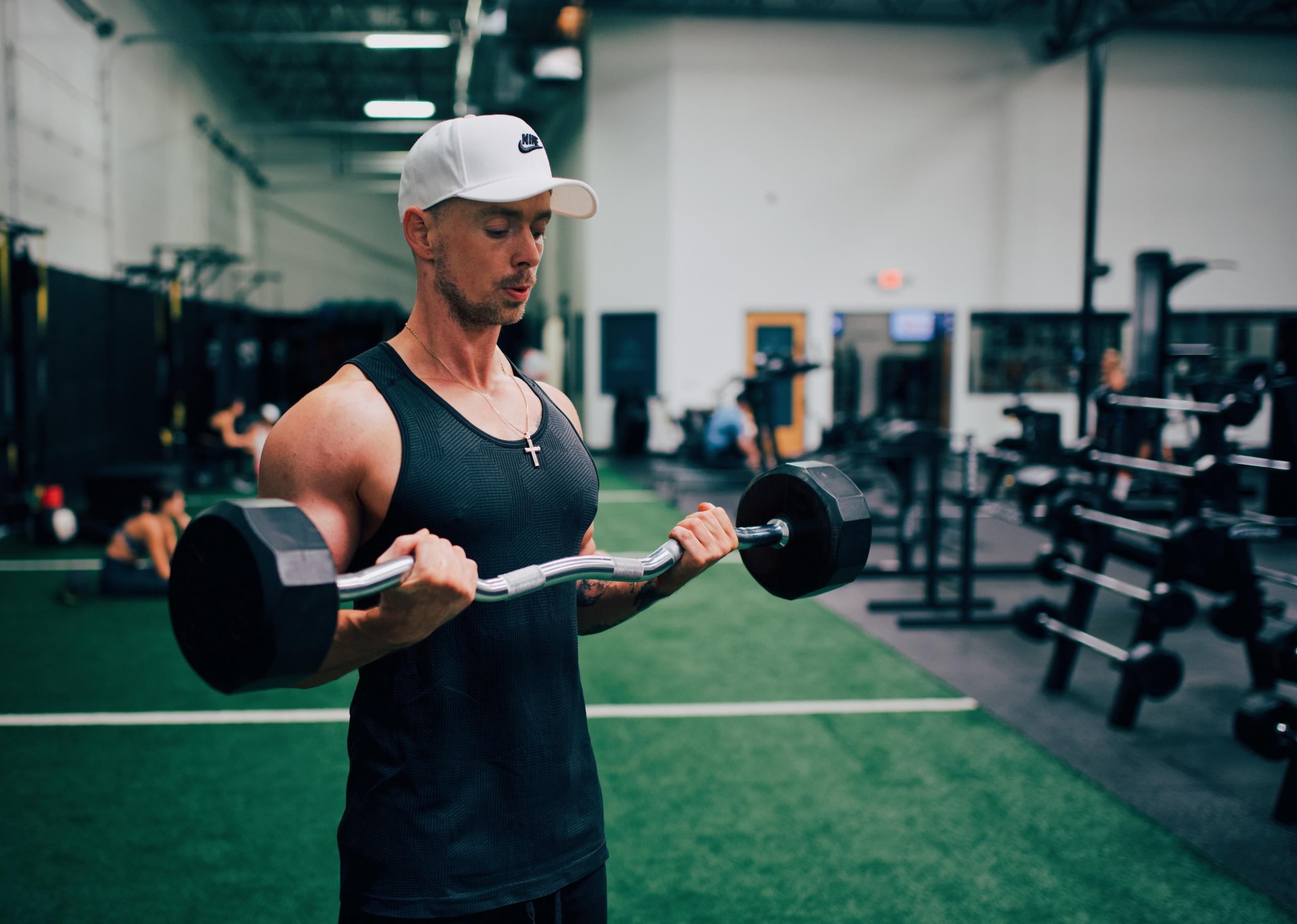en mann trener biceps med vekter på en stang