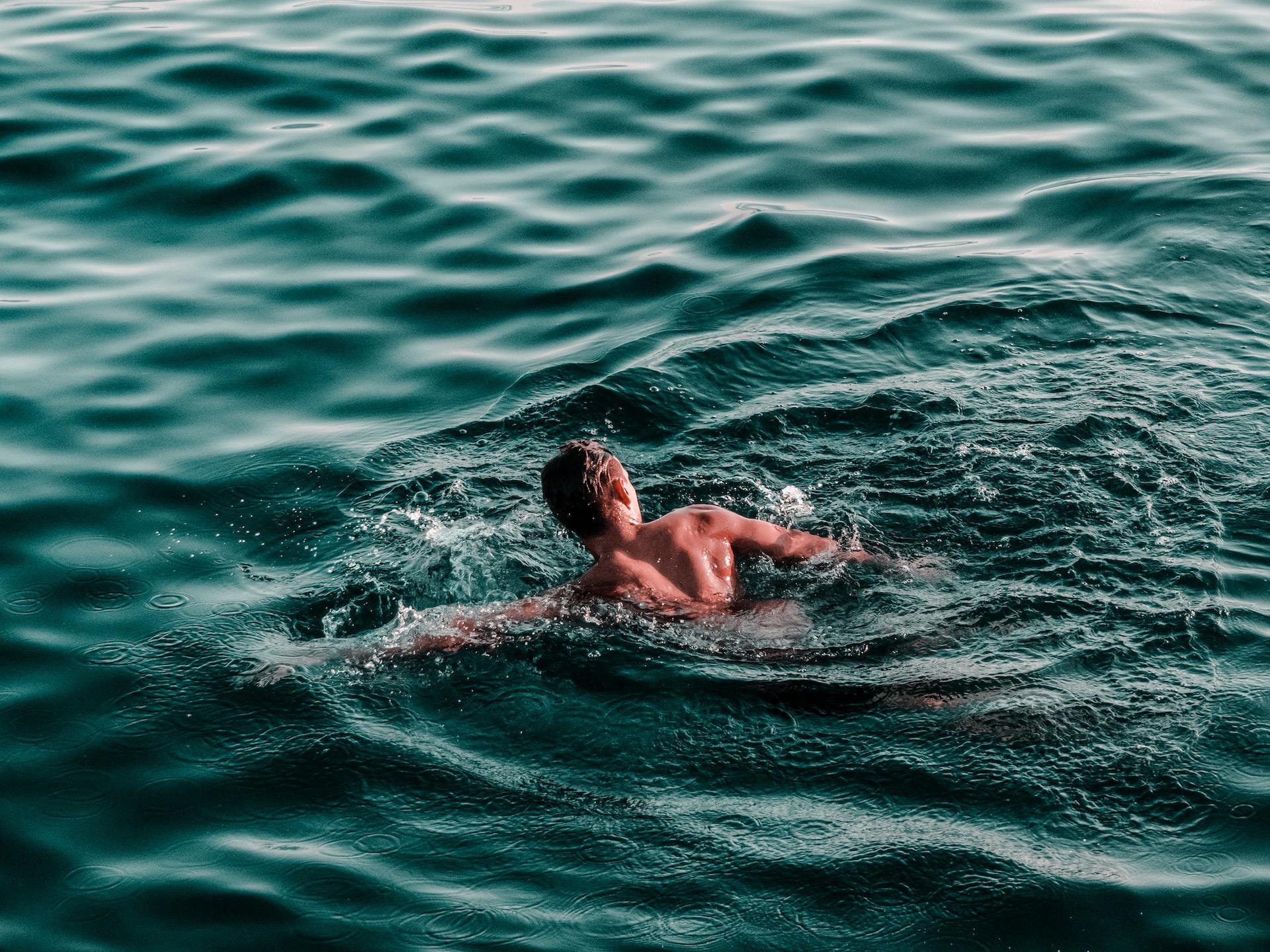 Mann svømmer i havet med crawlteknikk.