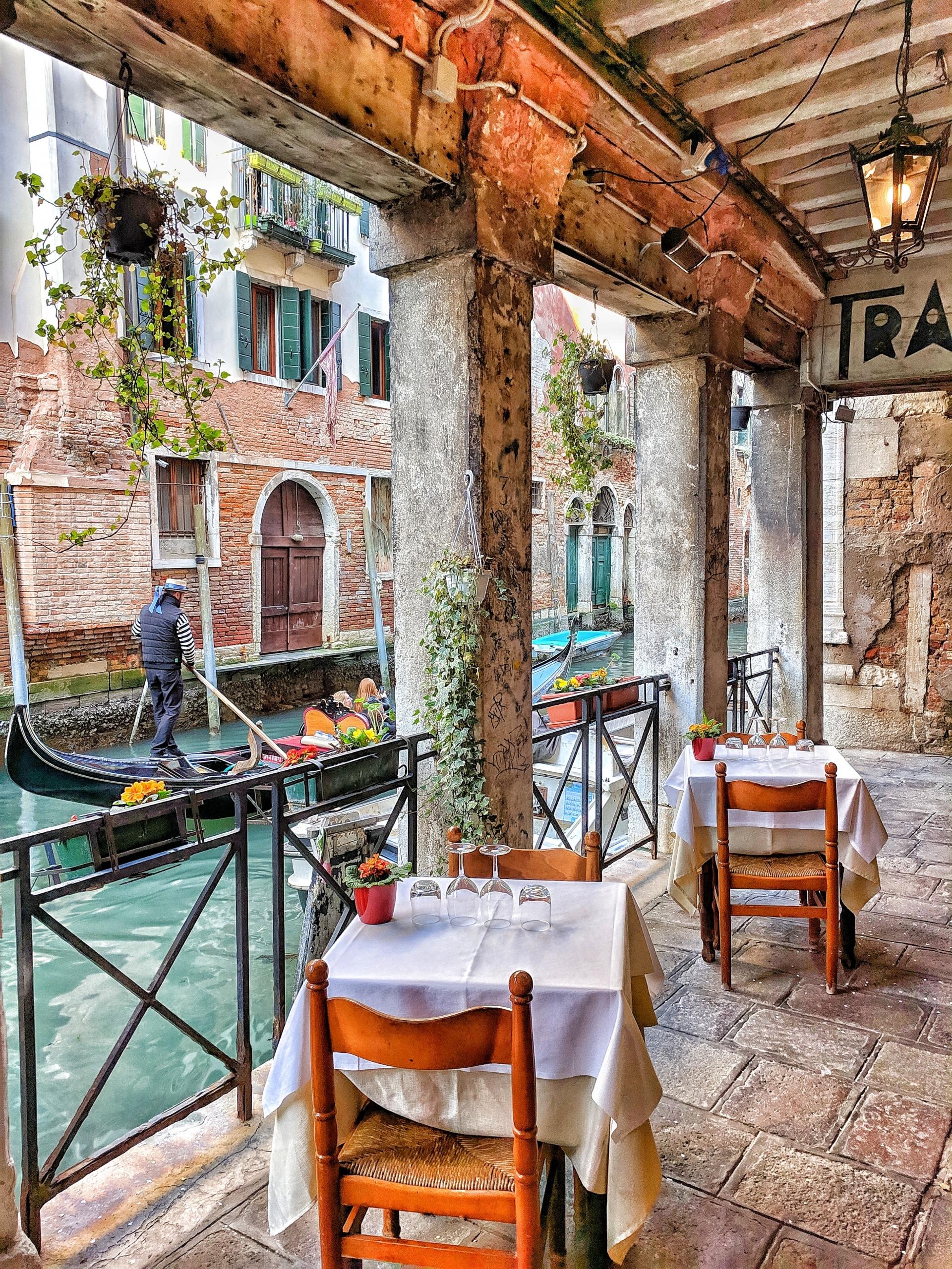 restaurant ved en kanal i venezia, en gondol flyter forbi