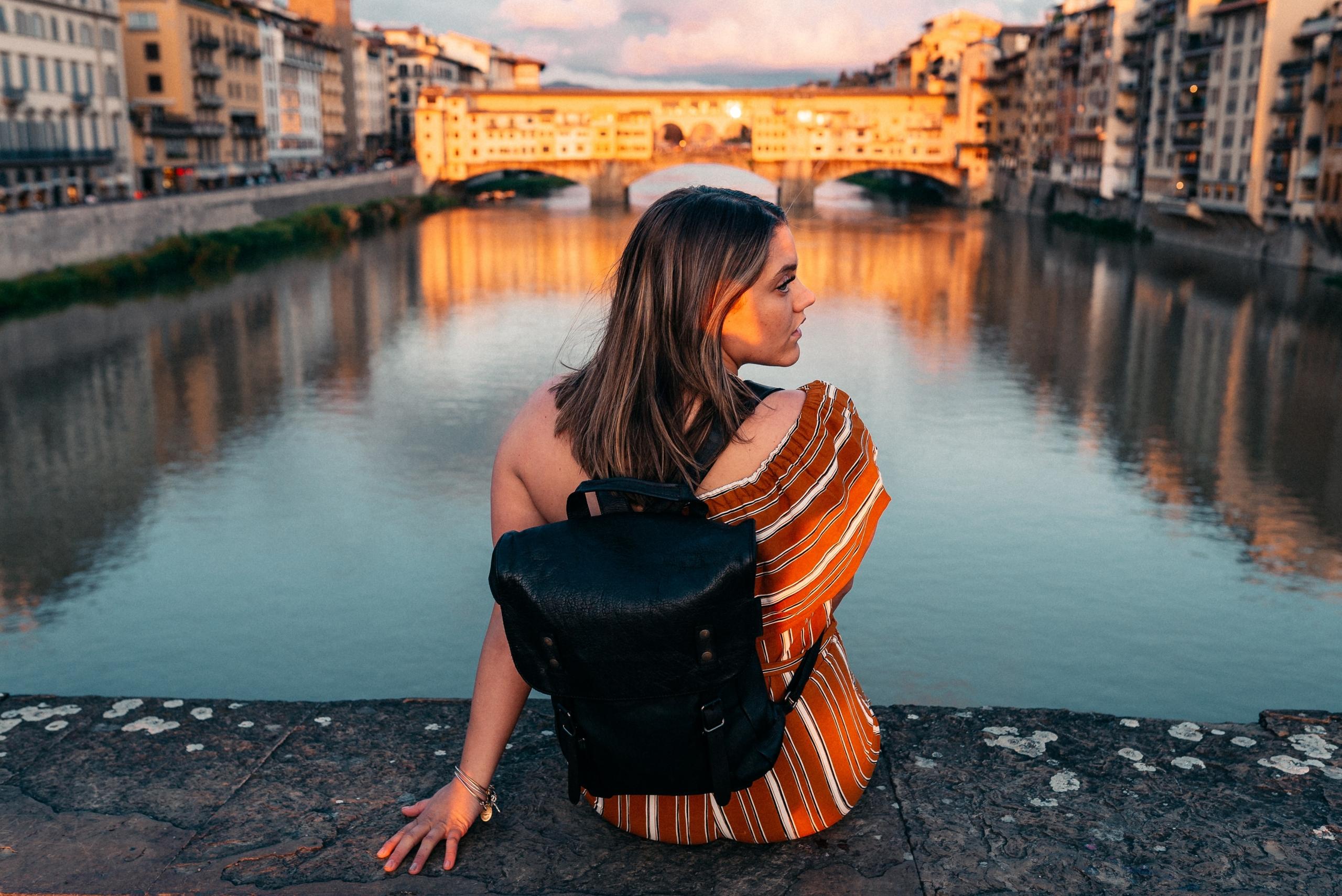 en ung kvinne er på ferie i firenze, hun sitter ved vannet