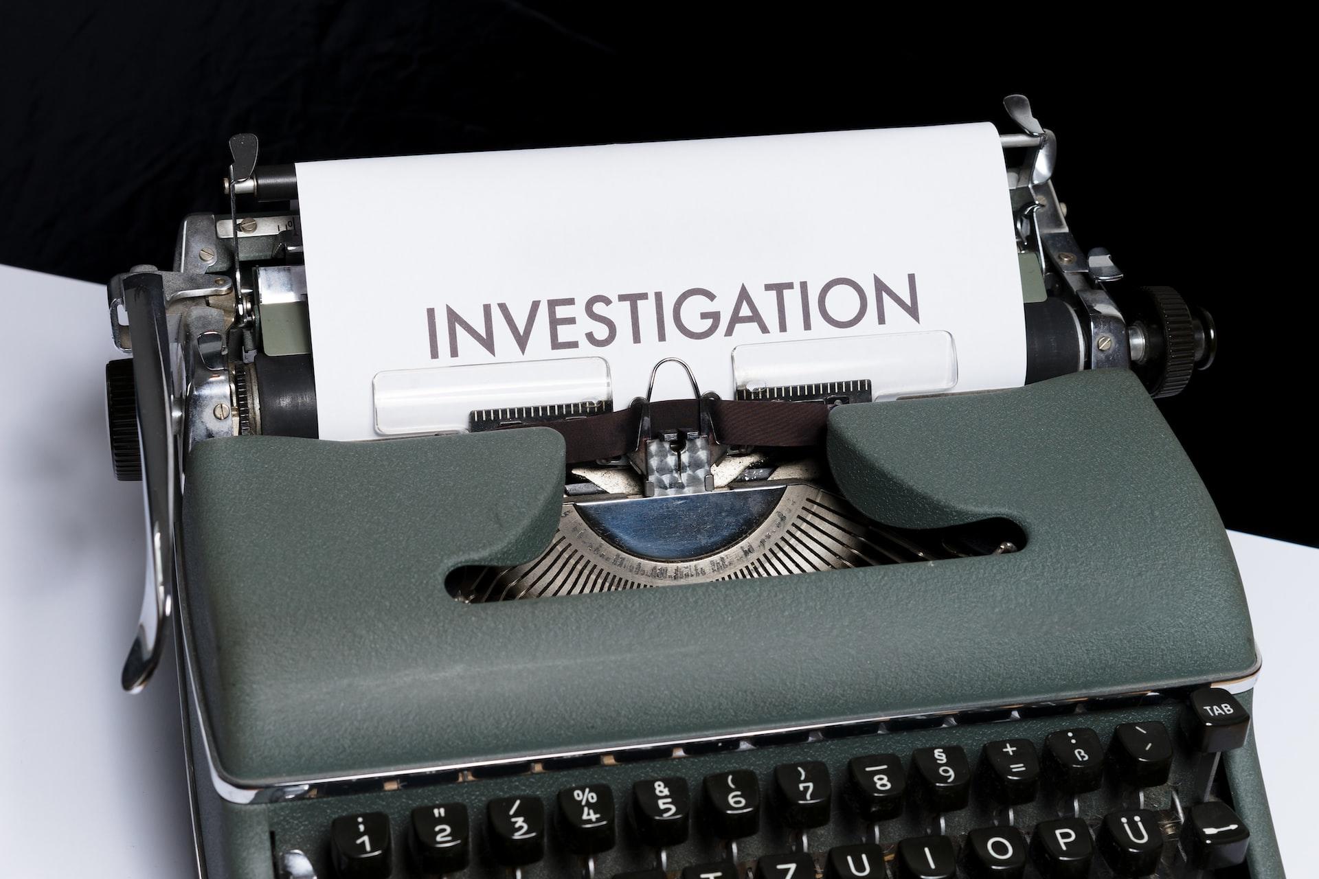 Gråblå skrivemaskin med ark som er skrevet ut hvor det står INVESTIGATION.