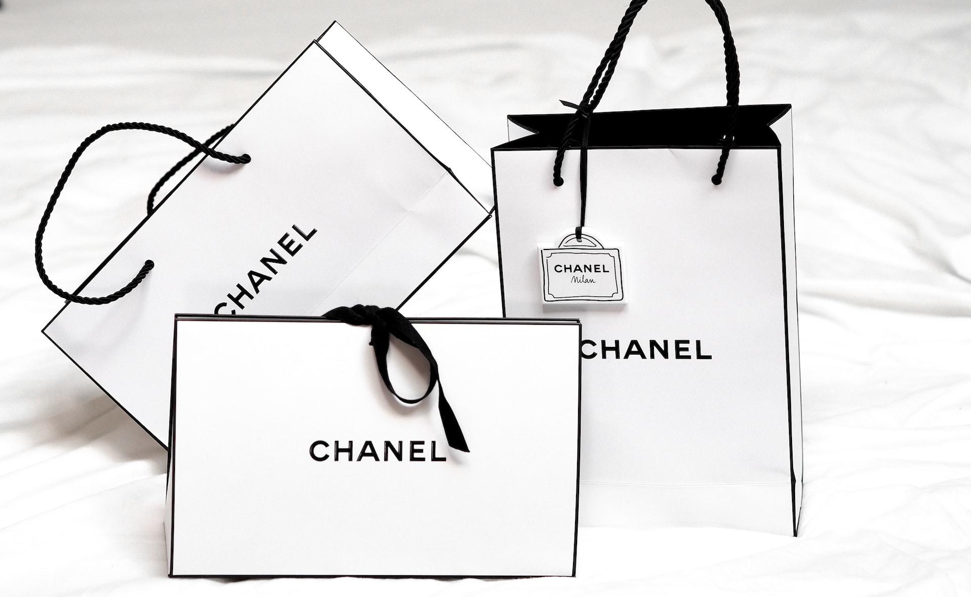 Tre hvite Chanel handleposer med sort kant og logo.