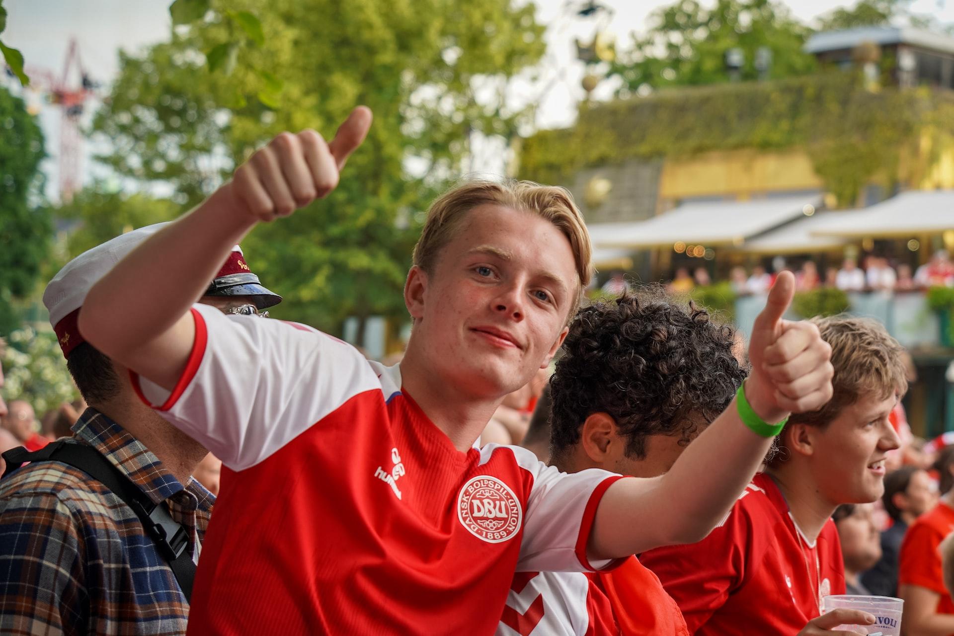 Blond gutt med dansk landslagsdrakt viser to tomler opp til kameraet.