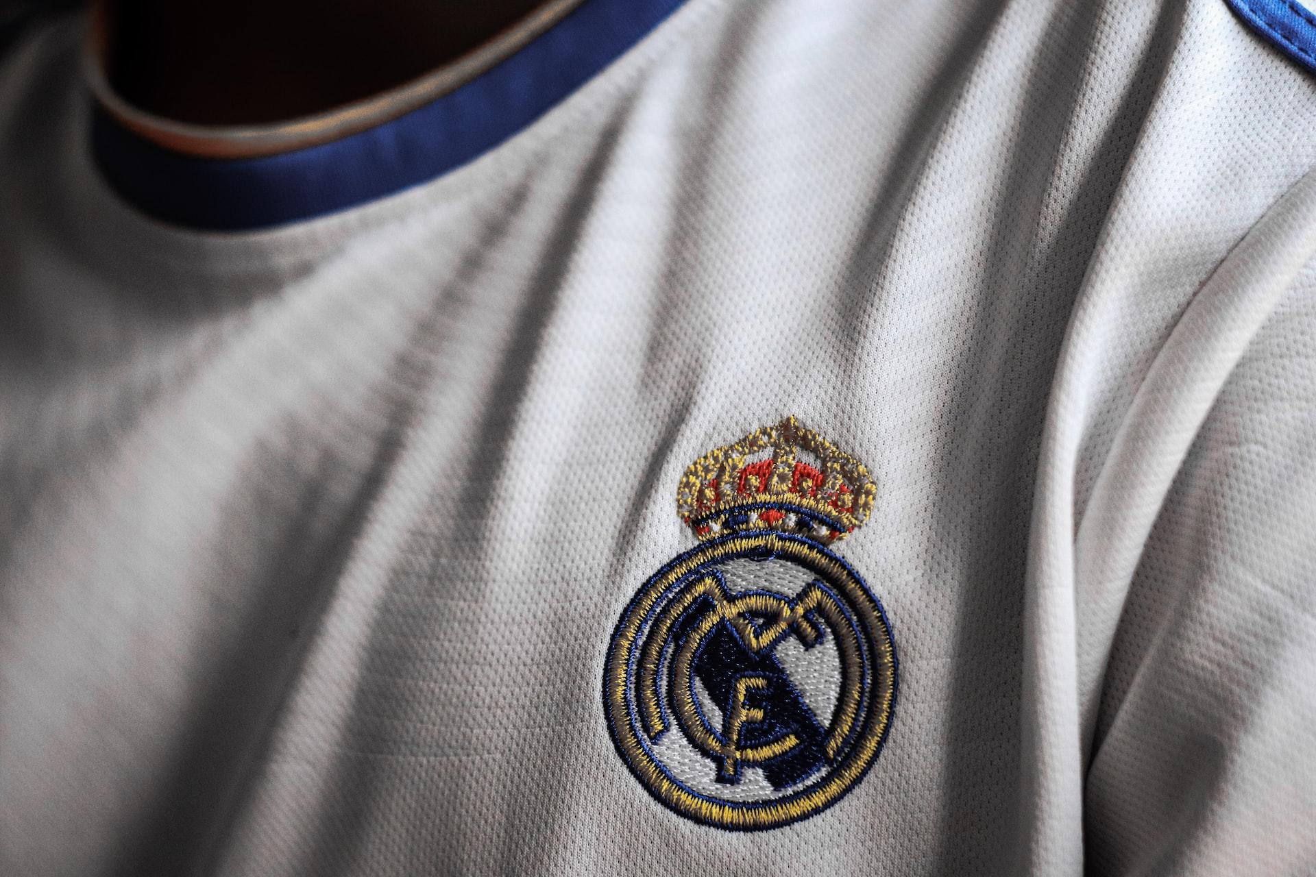 Nærbilde av logoen til Real Madrid på en hvit drakt.