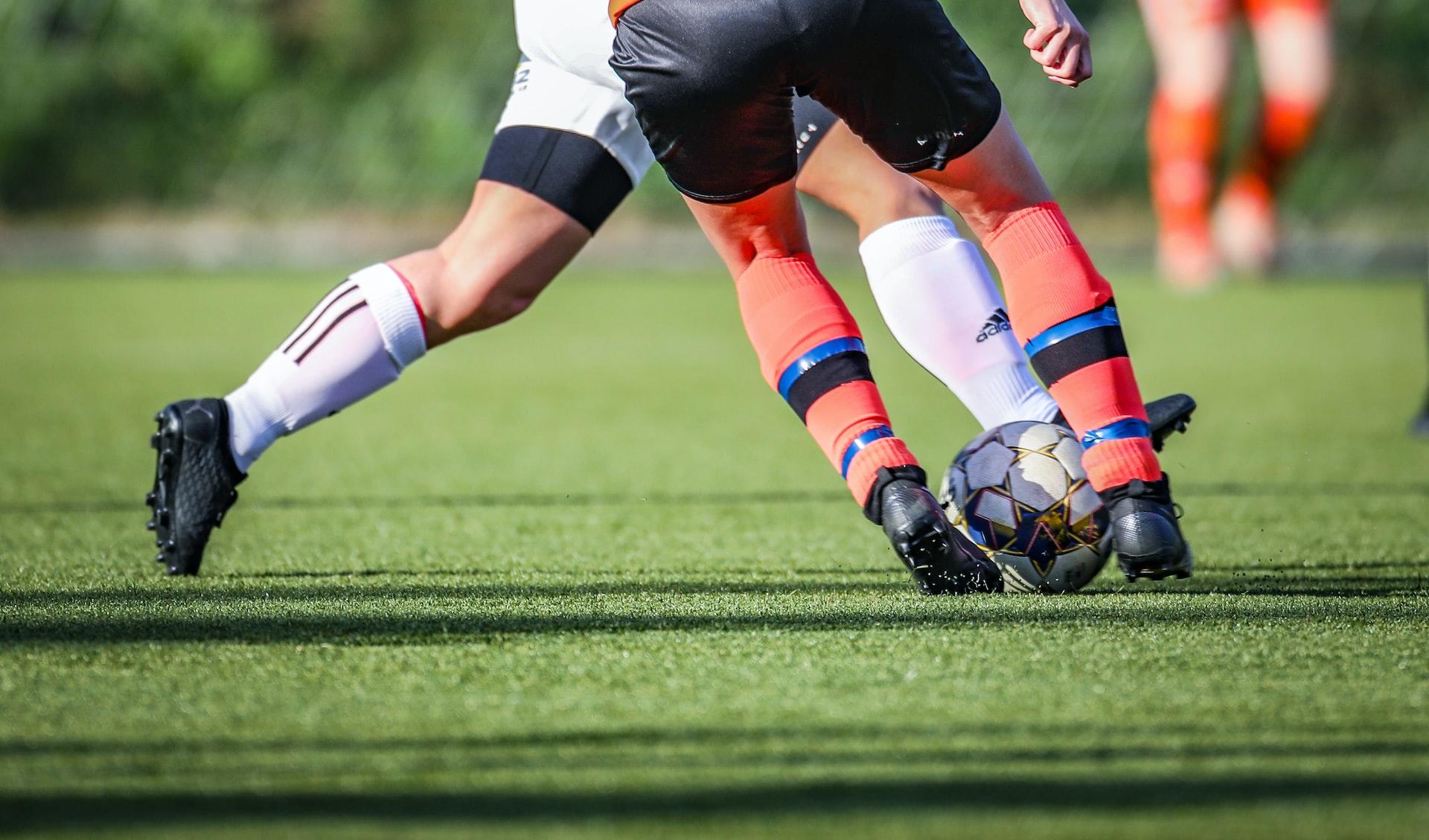Nærbilde av bein som løper mot samme fotball.
