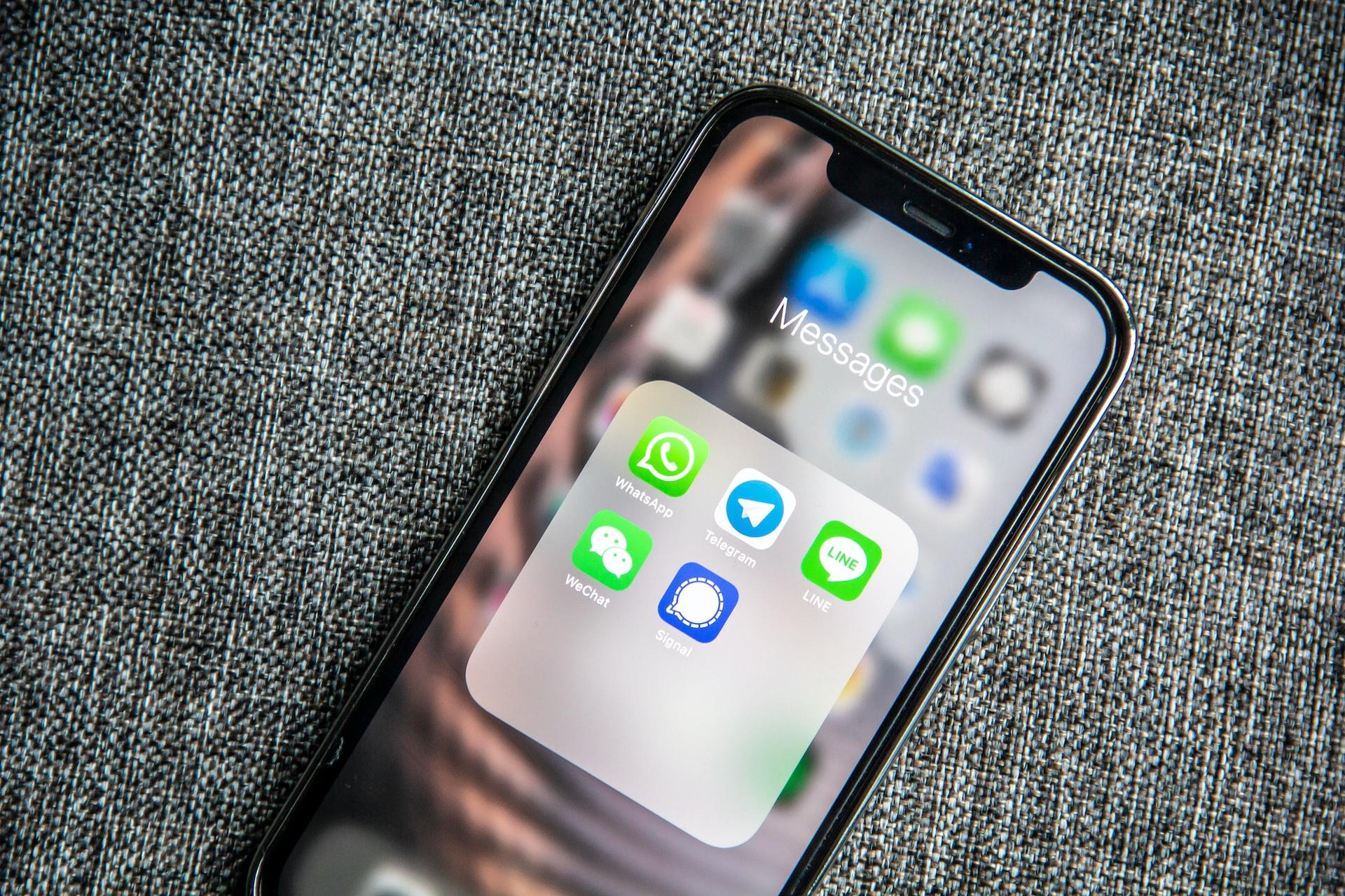 Nærbilde av en iPhone med ulike chatteapper i en mappe.