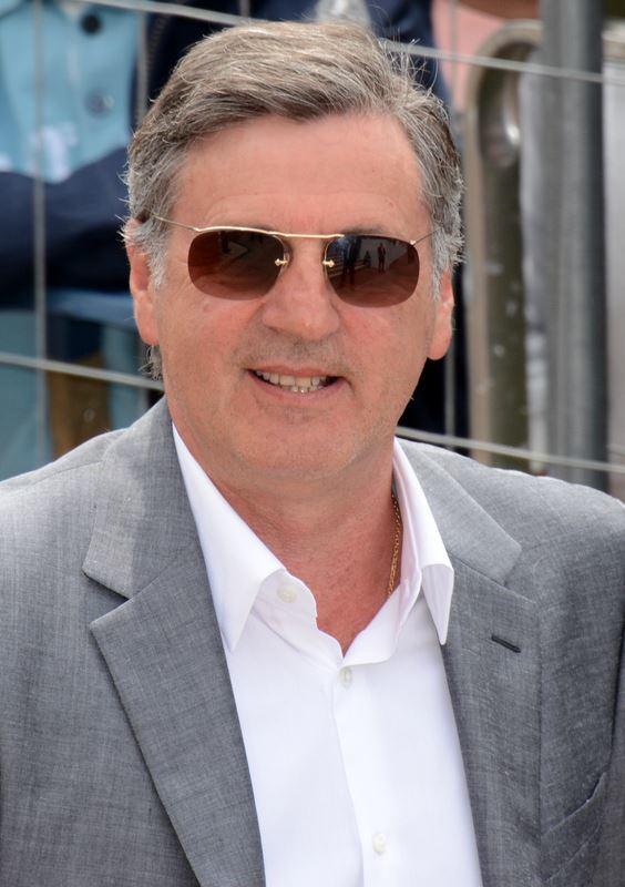 Daniel Auteuil med solbriller smiler til kamera.