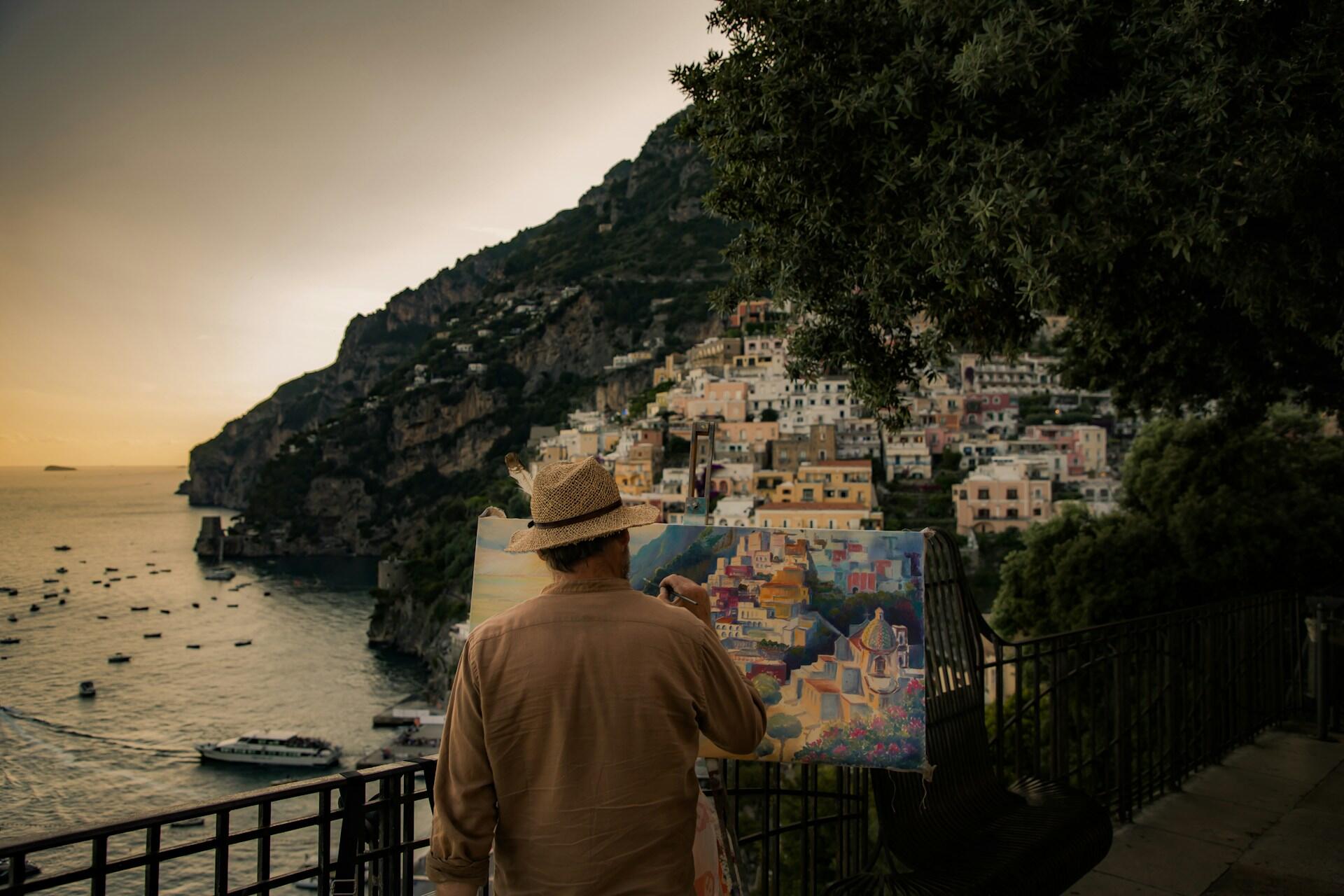 Maler ved staffeli med utsikt over Positano og Amalfikysten i Italia ved solnedgang