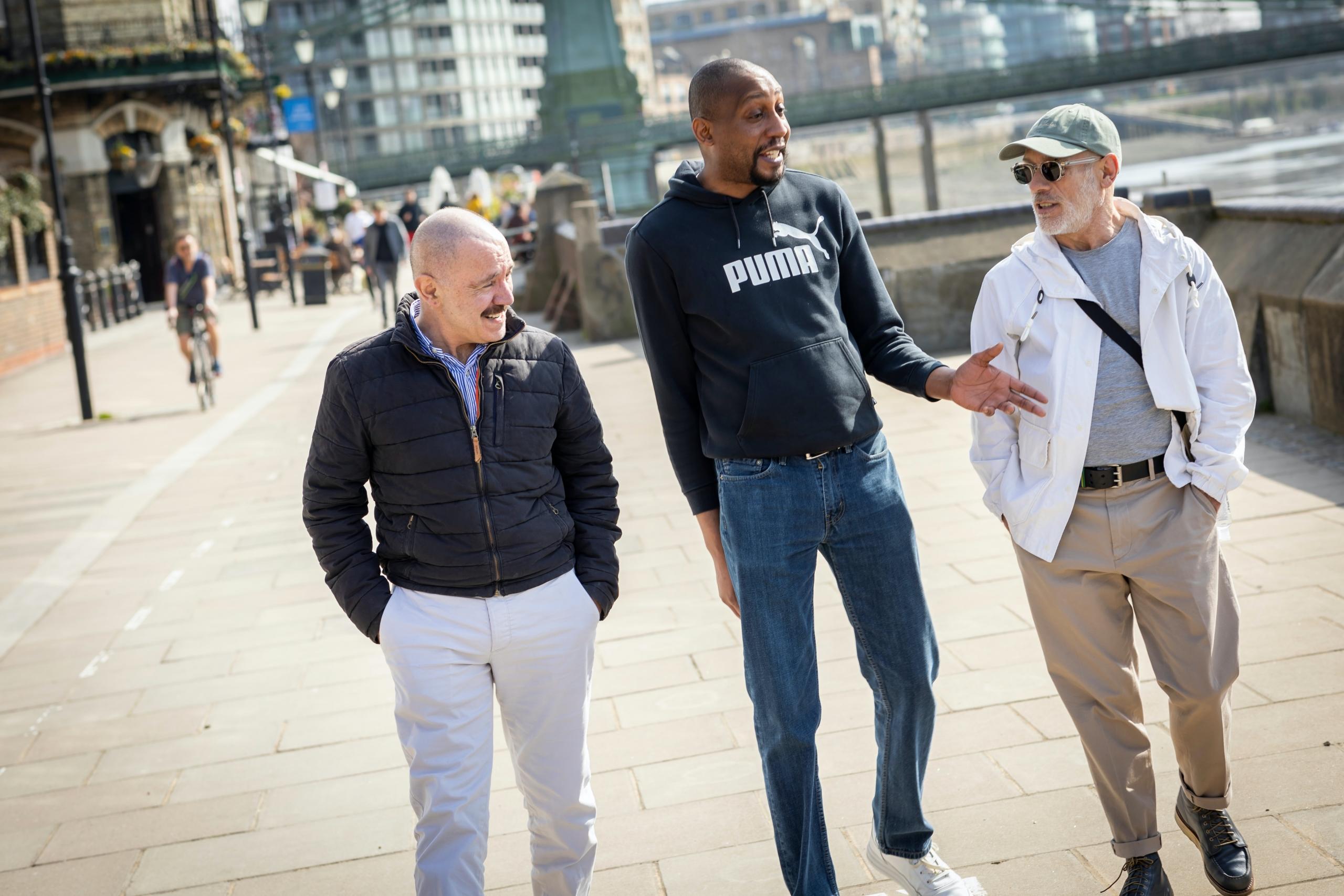 Tre mennfolk går tur og diskuterer i sentrum