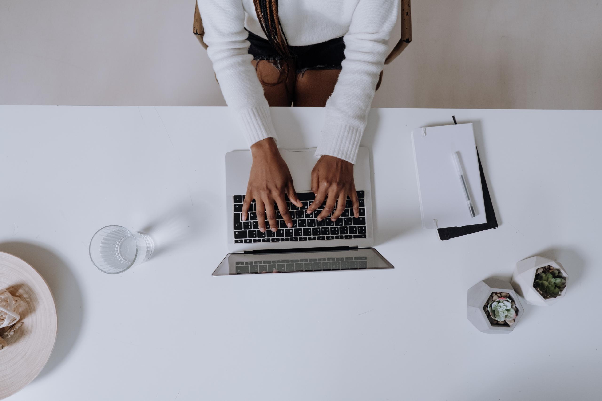 Undervisning på laptop, sitter på kontorstol med hendene over tastaturet