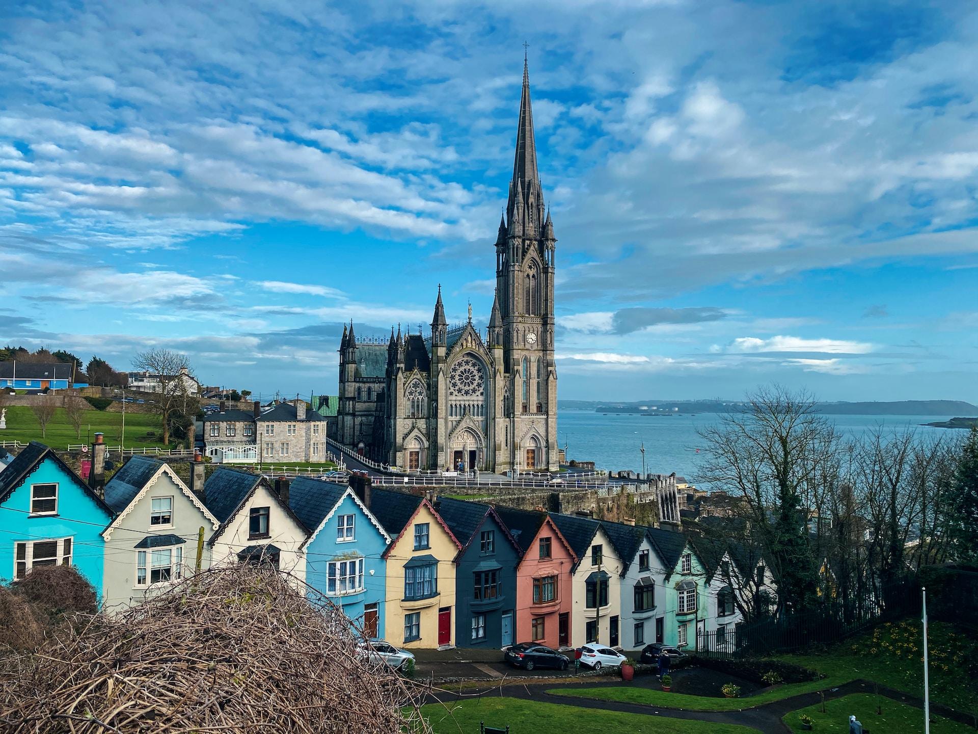 Kirke og fargerike trehus i byen Cork i Irland som ligger ved vannet.