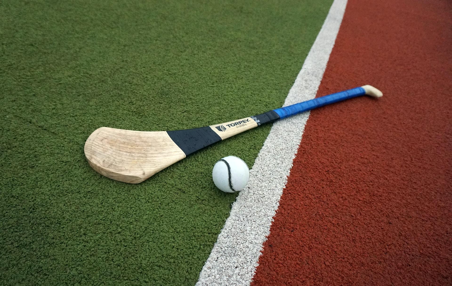Kølle og ball brukt i den irske sporten Hurling ligger på en farget bane.