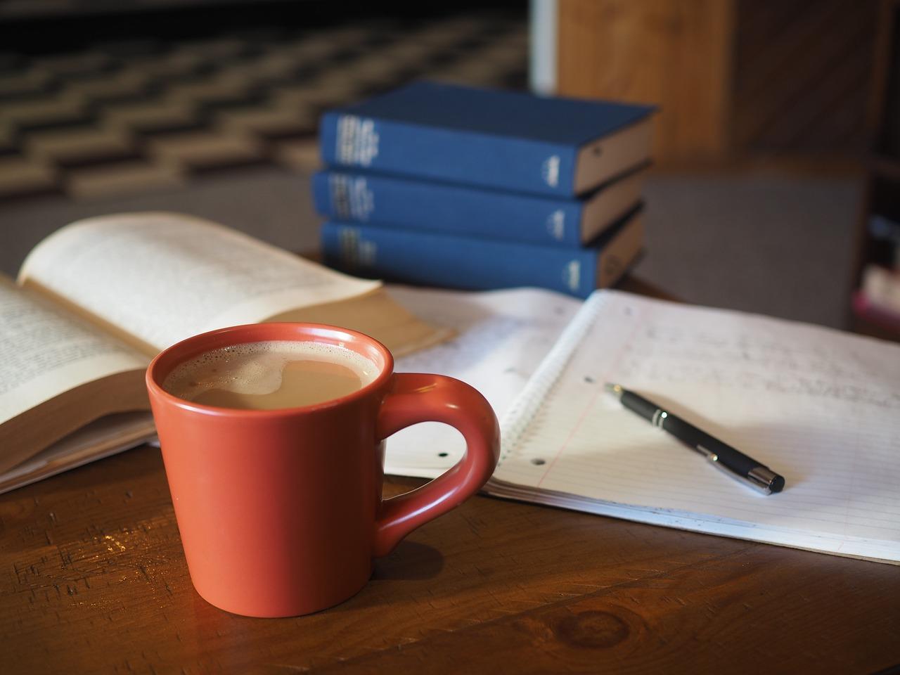 Leksebøker og kaffe på et bord med penn og papir