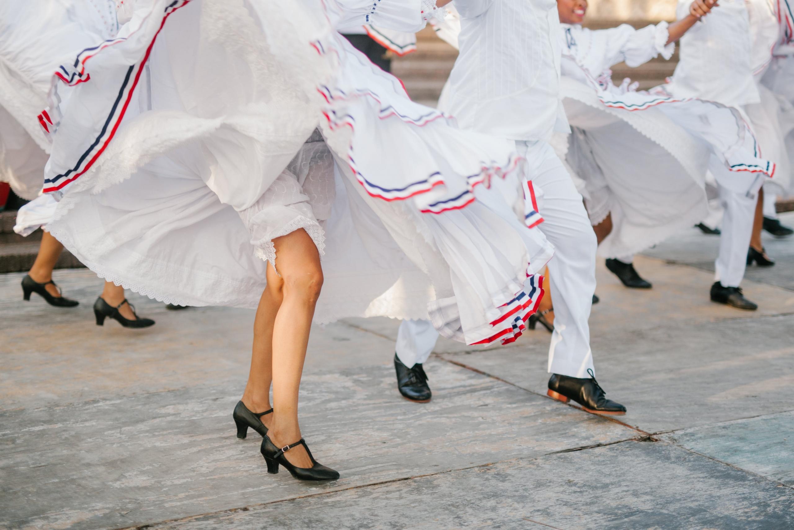 Profesjonelle flamenco-dansere i hvite kjoler danser på gaten hvor du kun ser skjørtene og bena