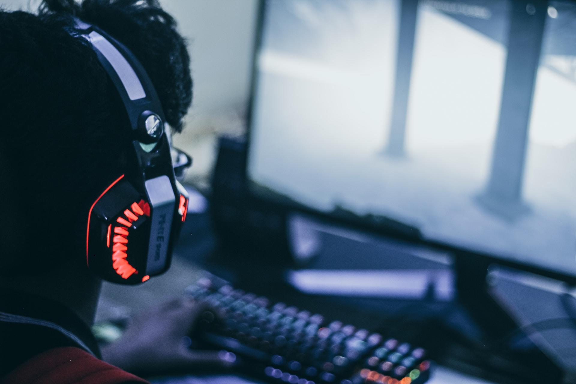 Mann med hodetelefoner gamer foran skjerm.