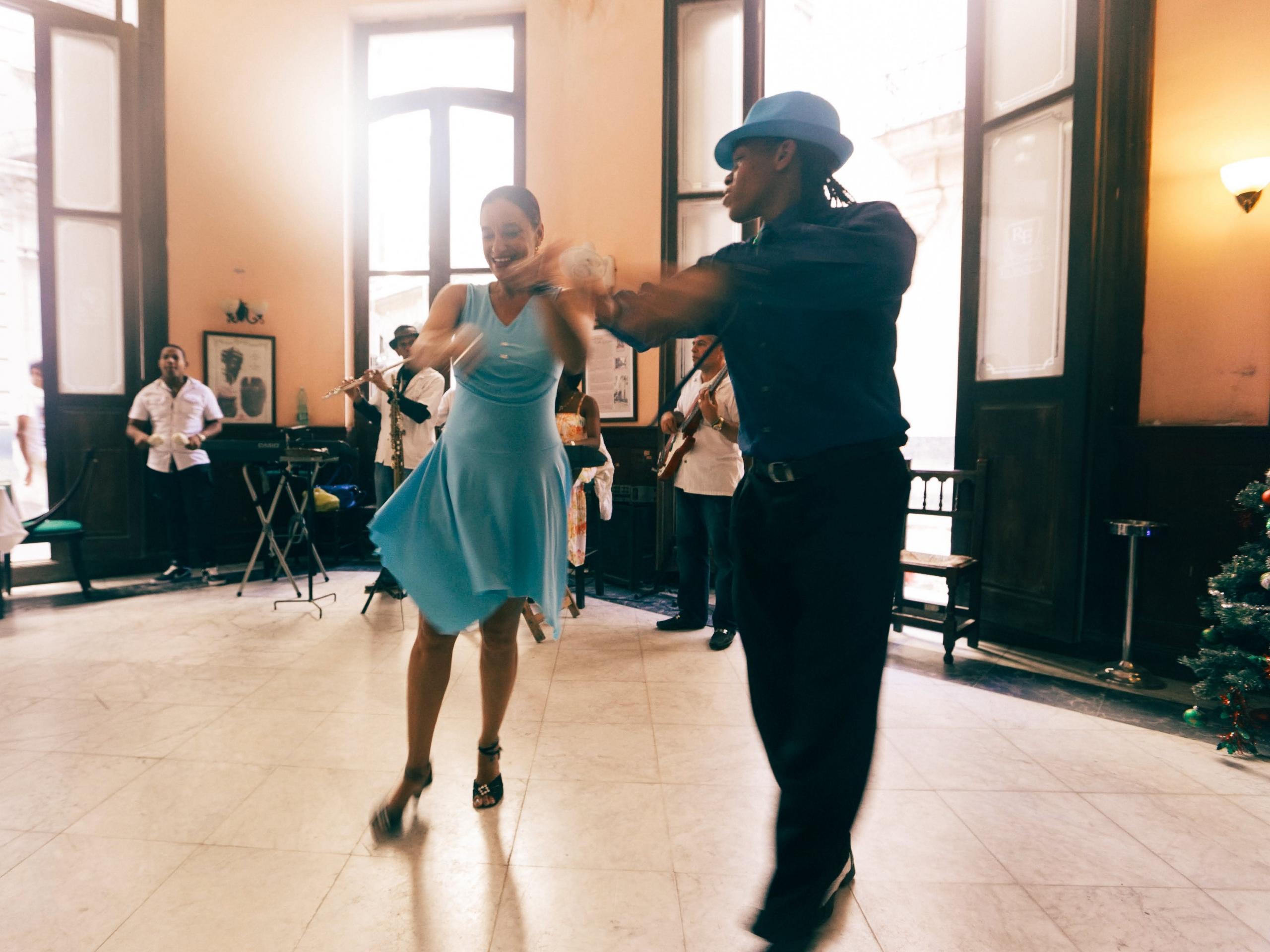 Mann og kvinne øver på å danse i en dansesal med kjole og dress på