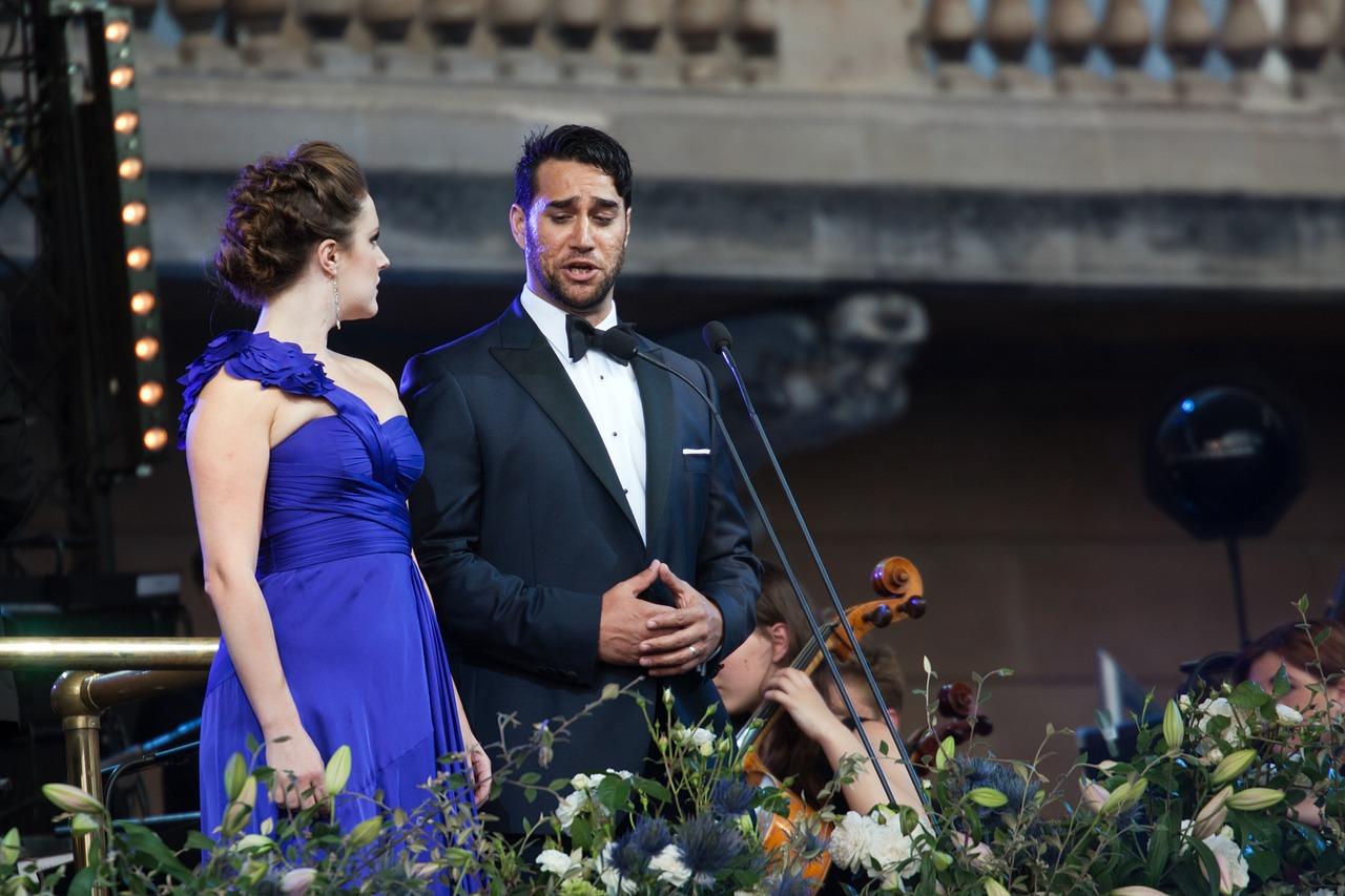 Kvinnelig og mannlig operasanger står side om side og synger opera