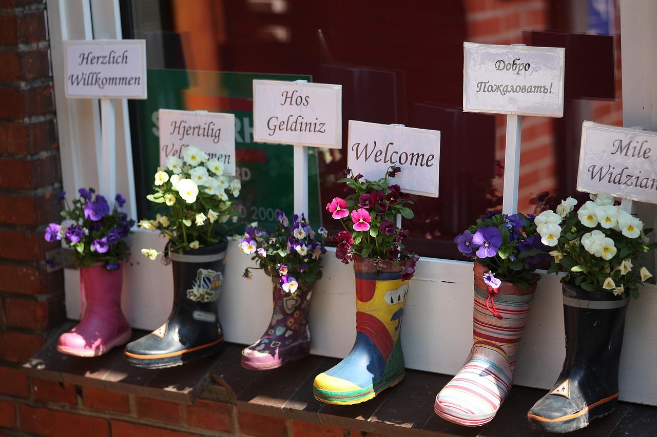 Flere blomsterkrokker med skilt for velkommen på flere språk.