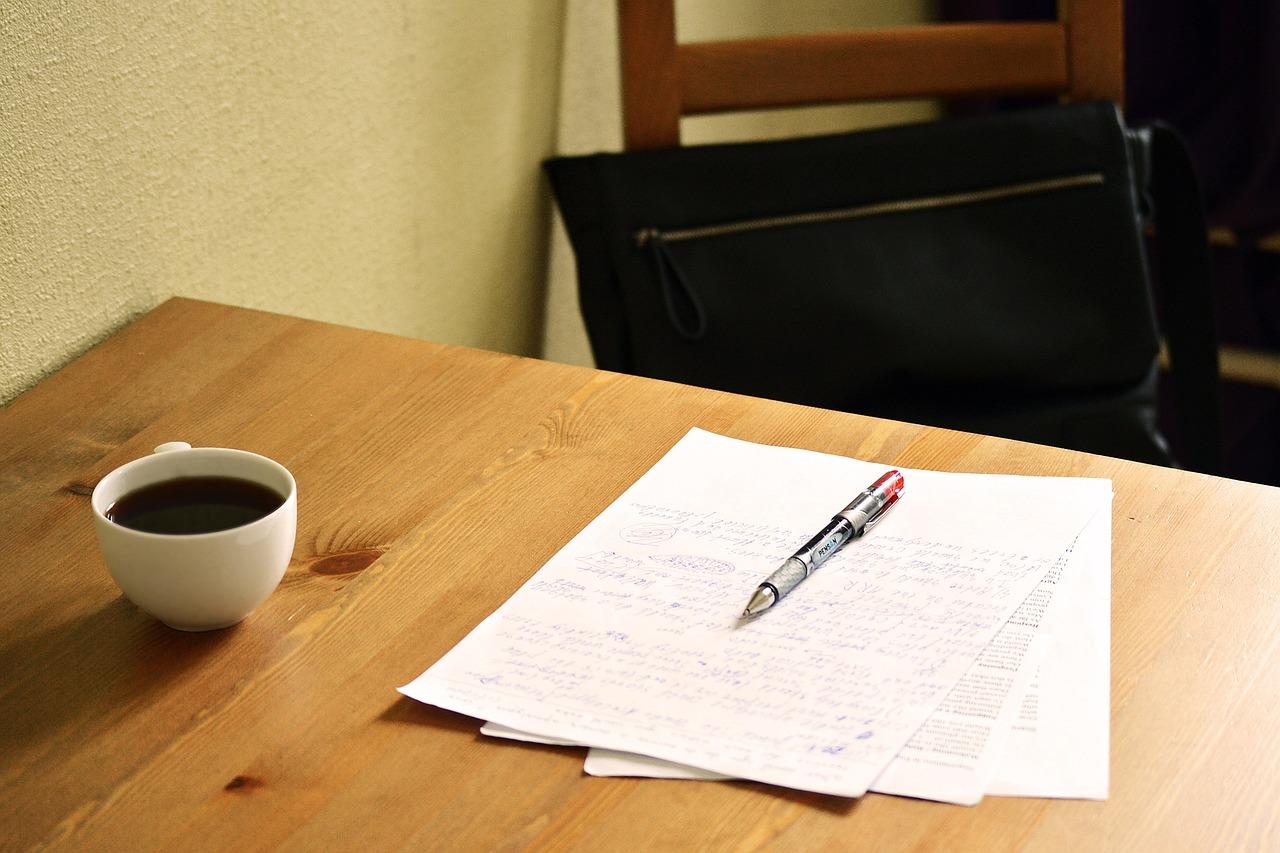 Papir, penn og kaffekopp på skrivebordspult