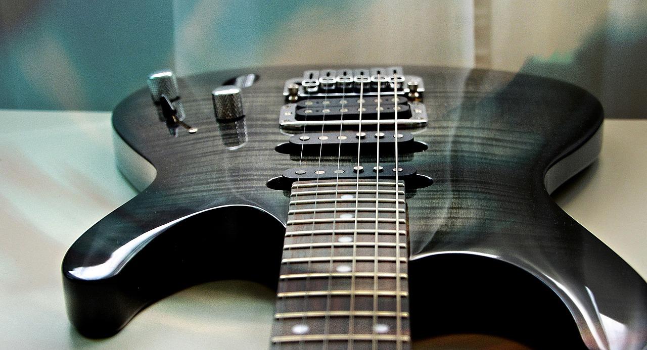 Sort elgitar som ligger på hvitt bord