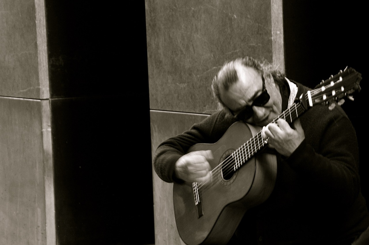 Mann spiller på flamenco gitar sittende med solbriller på
