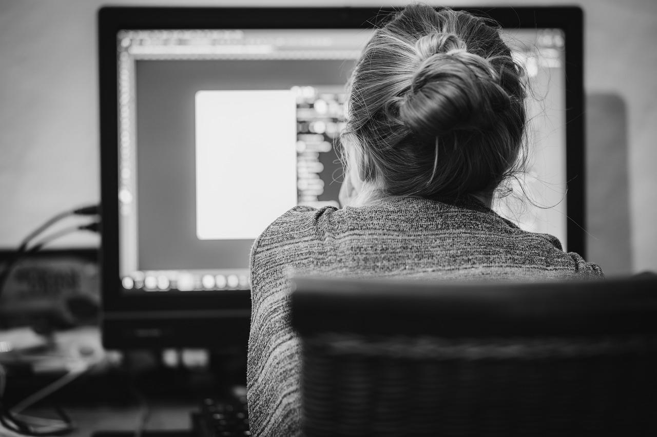 Kvinne leser seg opp i business engelsk og sitter med bakhodet vendt mot en skjerm i sort-hvitt