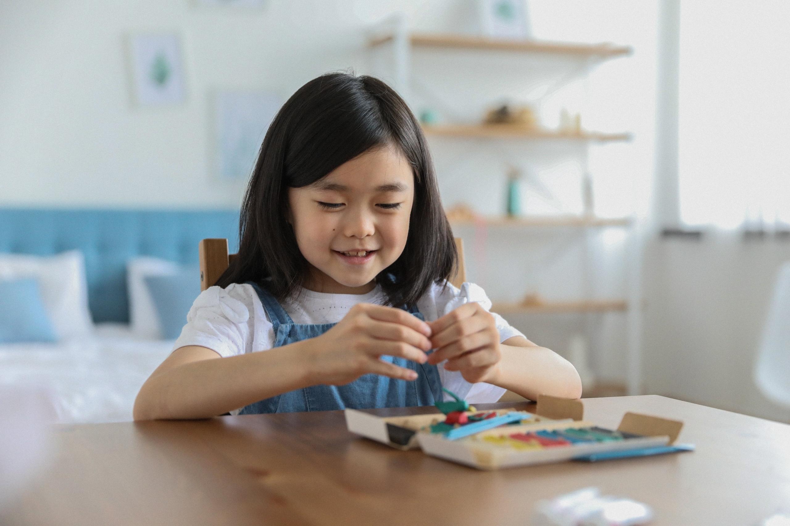 Et smilende barn som leker med fargerike pedagogiske spill på et bord.