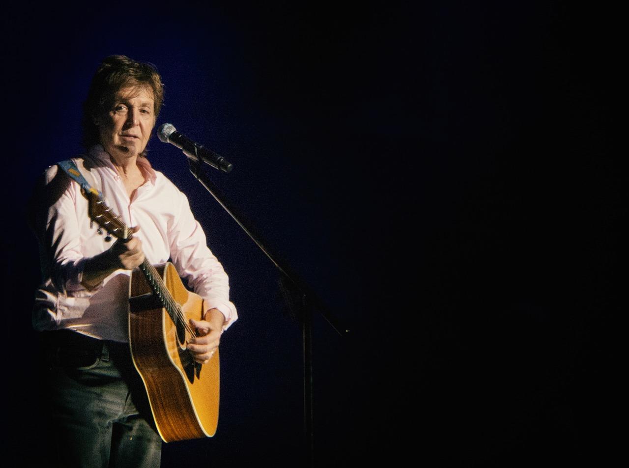Paul McCartney på scenen med akustisk gitar i hendene og mikrofon