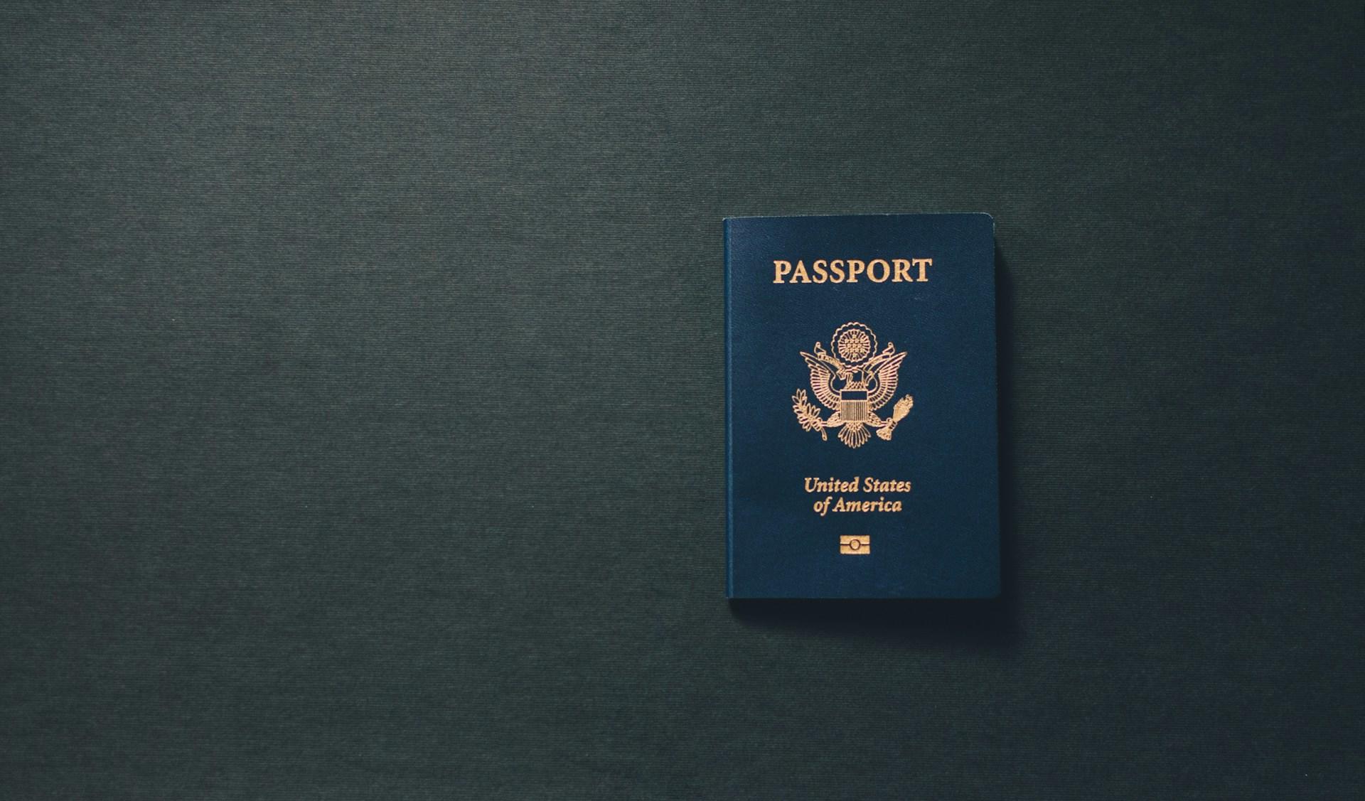 Mørkeblått amerikansk pass med gullskrift ligger på et sort bord.