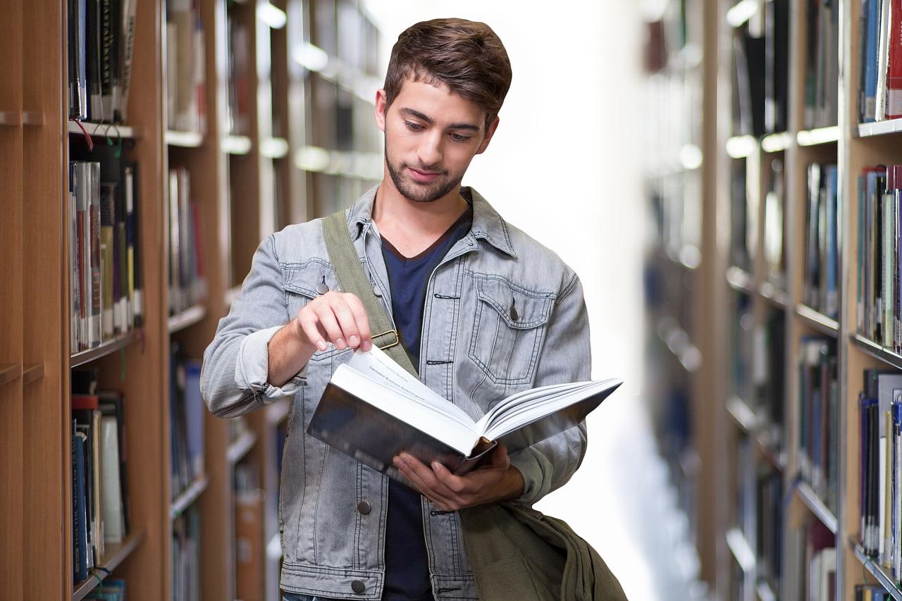 Student som leser en bok i biblioteket.