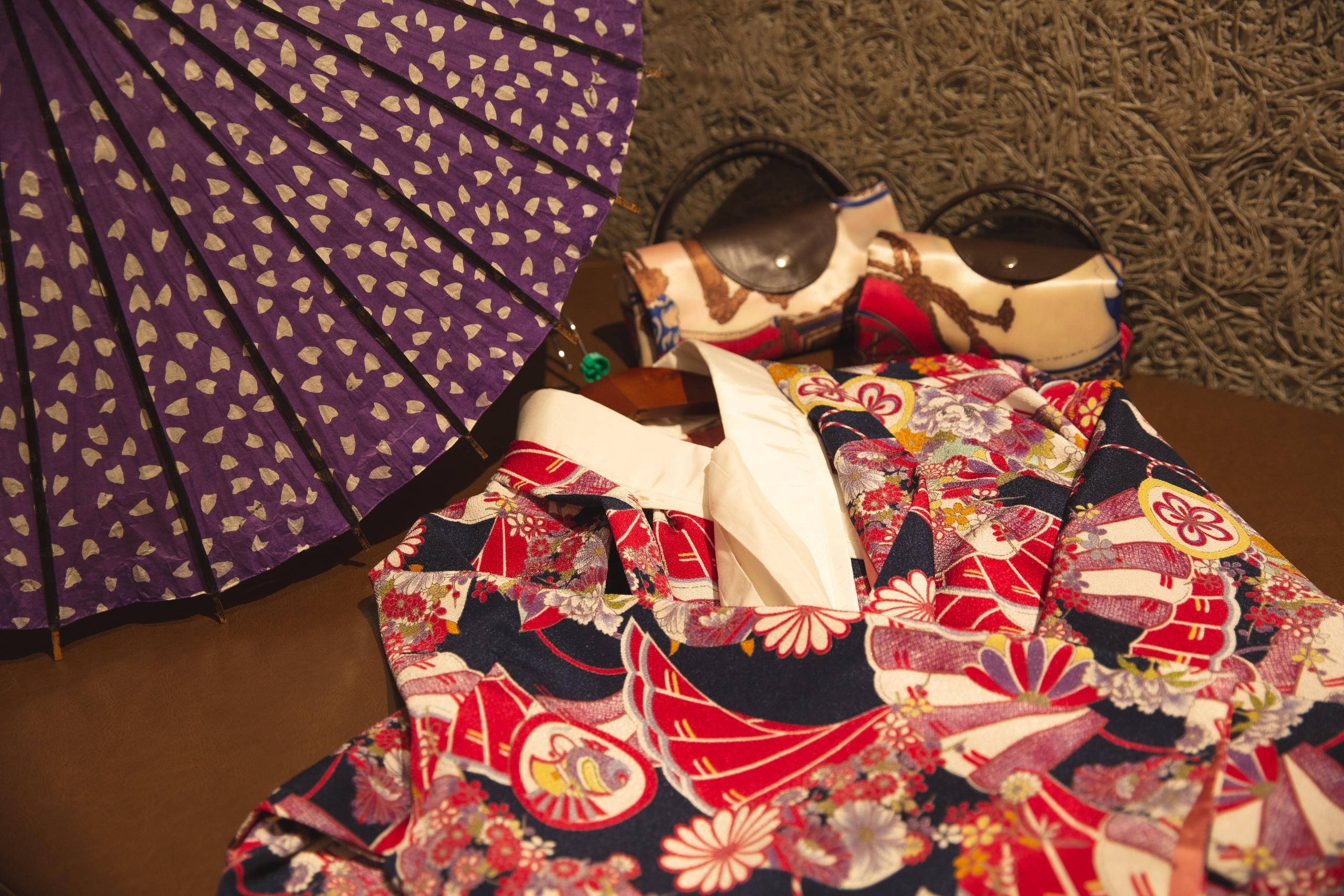 Et nøye arrangert utvalg av geisha-tilbehør, inkludert en vifte, kimono og tradisjonelle sandaler.