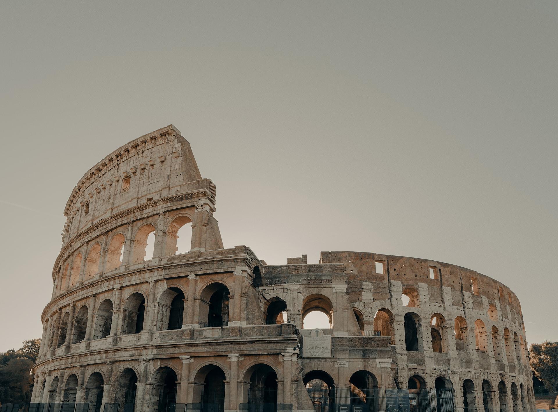 Colosseum i Italia med sola som går ned i bakgrunnen.