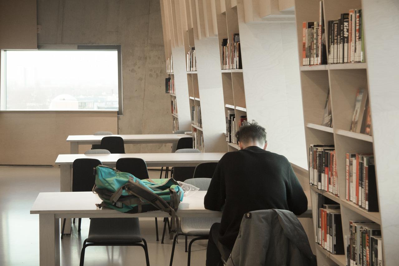 Ensom student som forbereder seg til eksamen i et stille bibliotek.