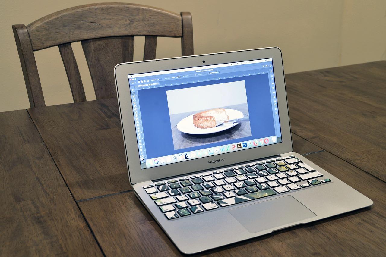 En åpen MacBook Air med et bilde av en tallerken og et stykke kake på skjermen.