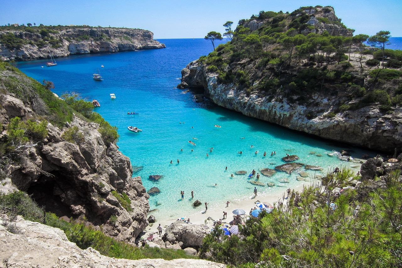 En bortgjemt bukt med turkisfarvet vann og folk som nyter solen på Mallorca.