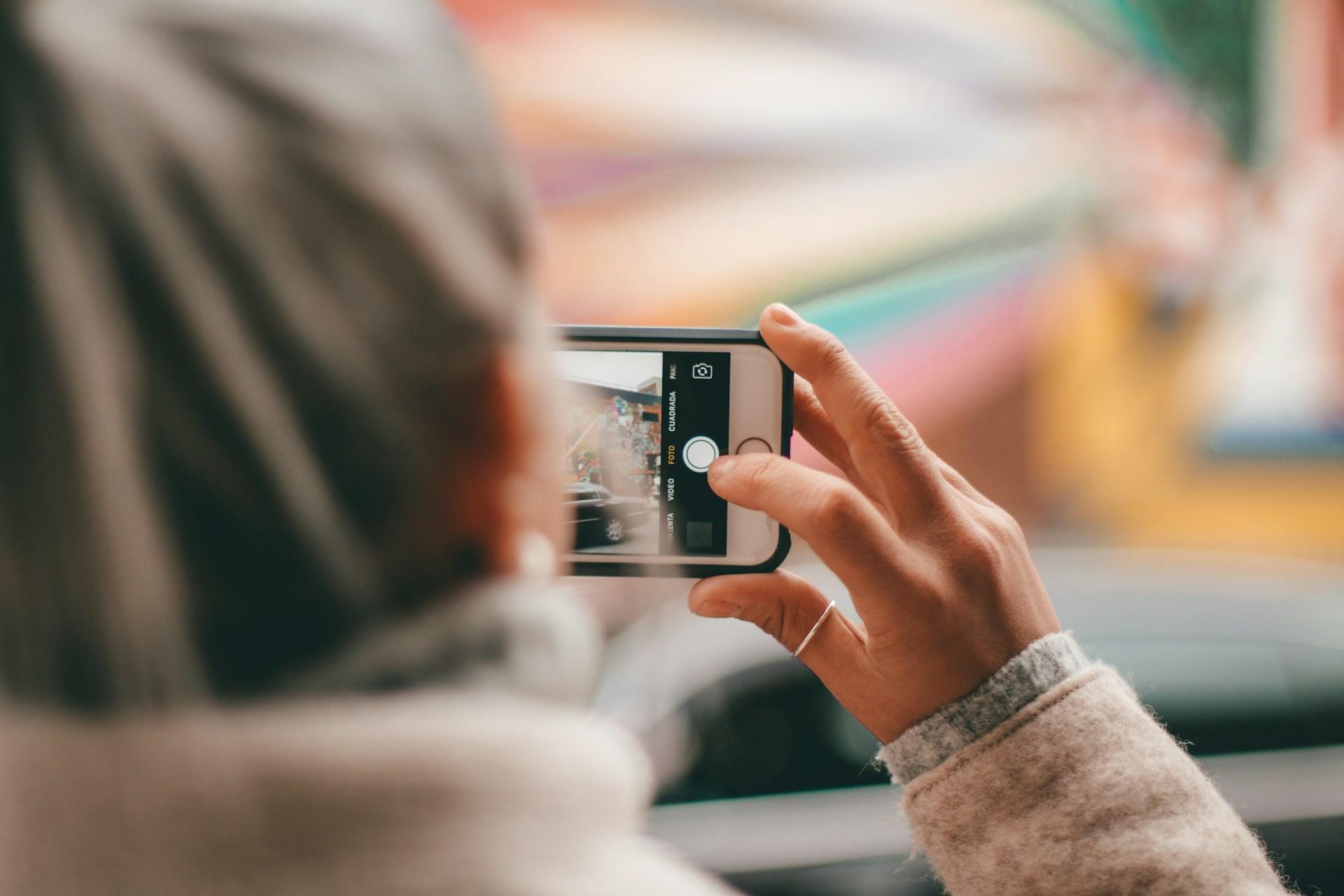 Dame tar bilde med mobiltelefonen sin, som hun holder sidelengs.